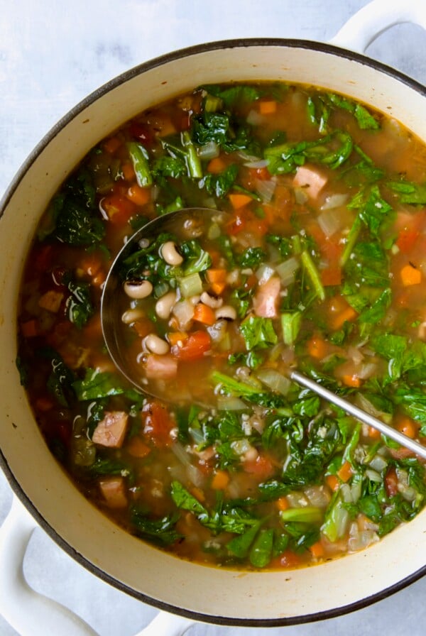 Black-Eyed Pea Soup in white Dutch oven with soup ladle.