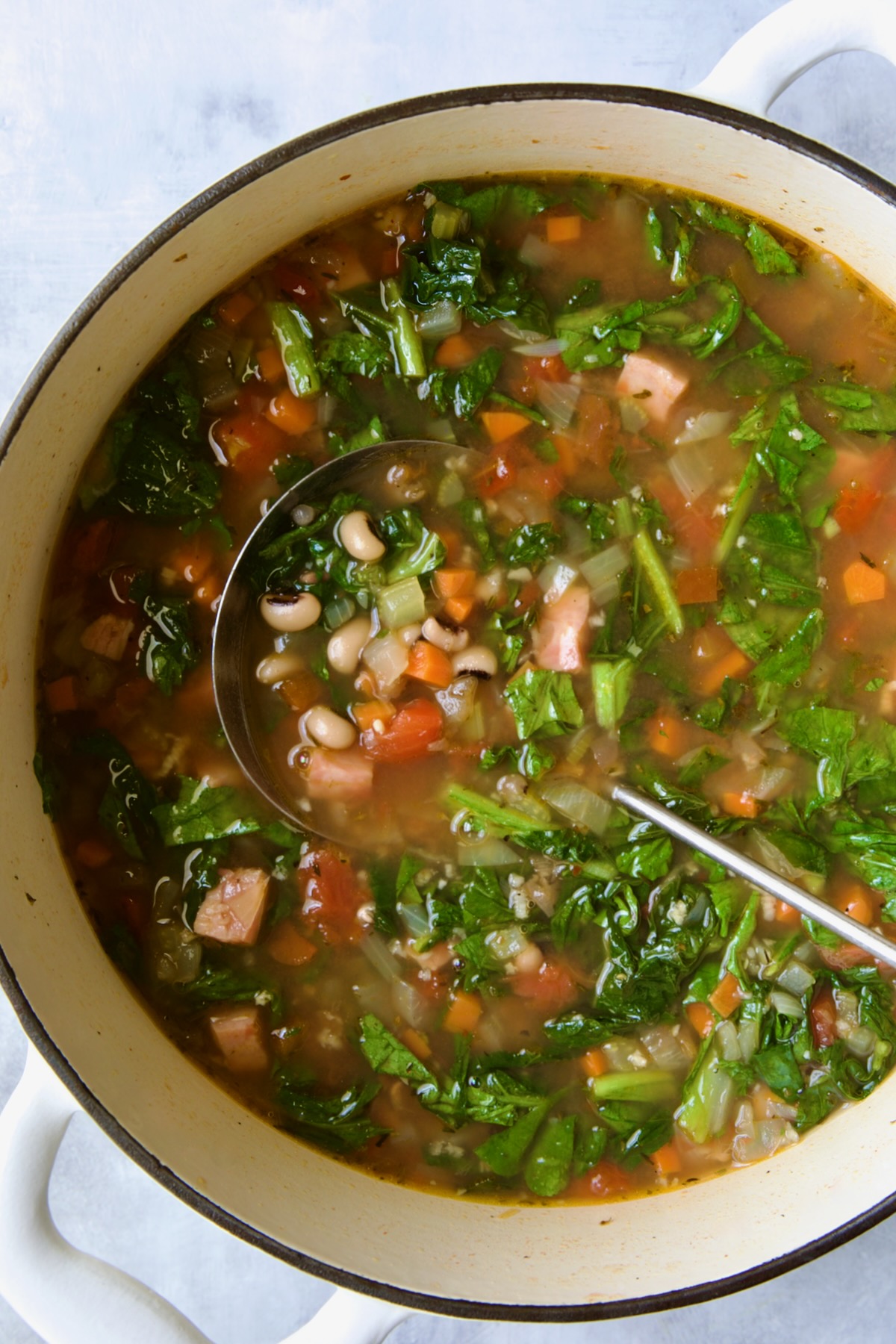 Black-Eyed Pea Soup in white Dutch oven with soup ladle.