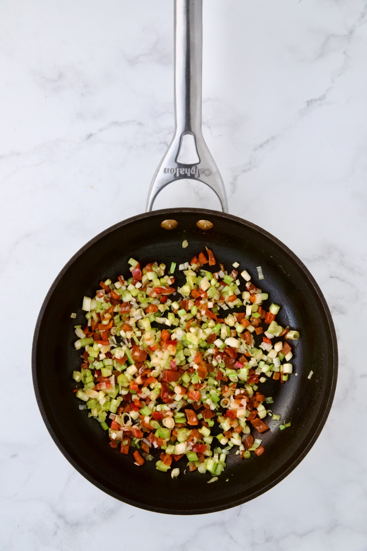Cooked scallions and red bell pepper in nonstick skillet.