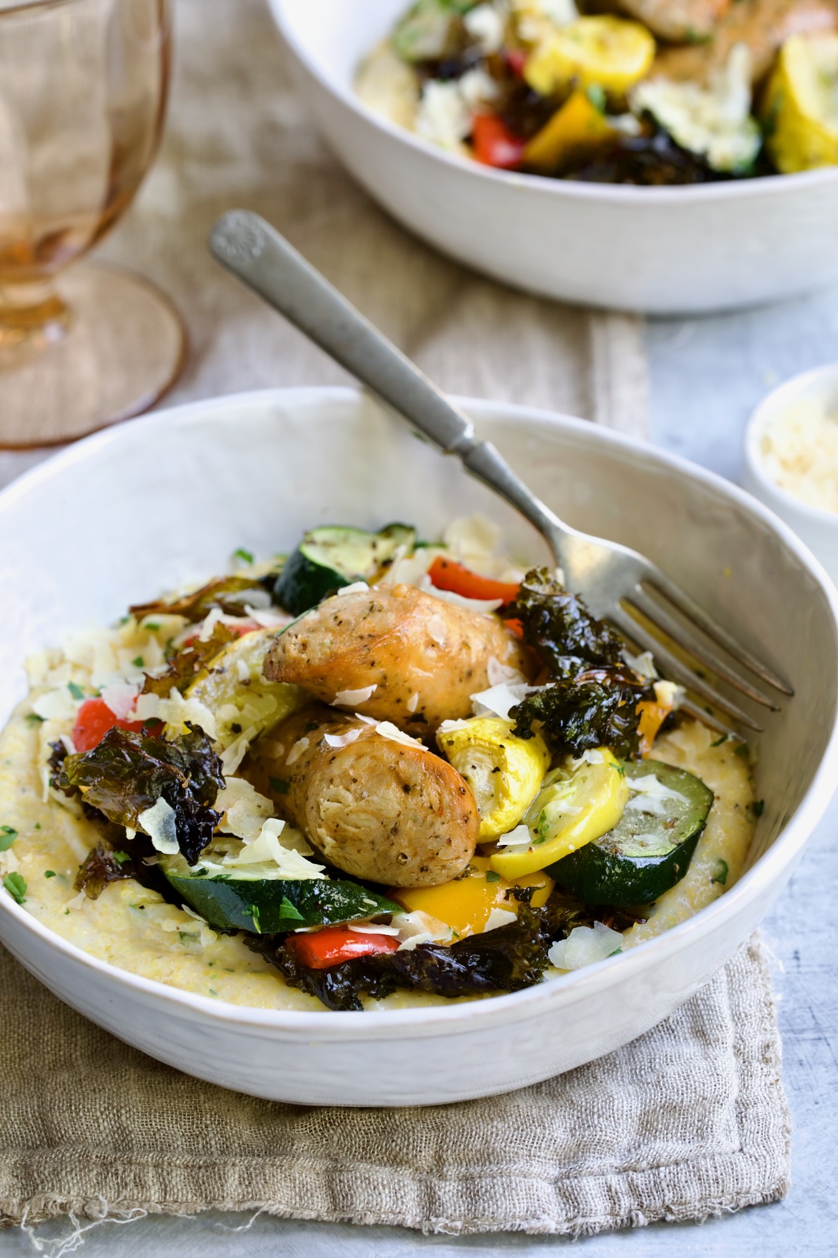 Chicken Sausage Sheet Pan and Polenta in white bowl with fork.