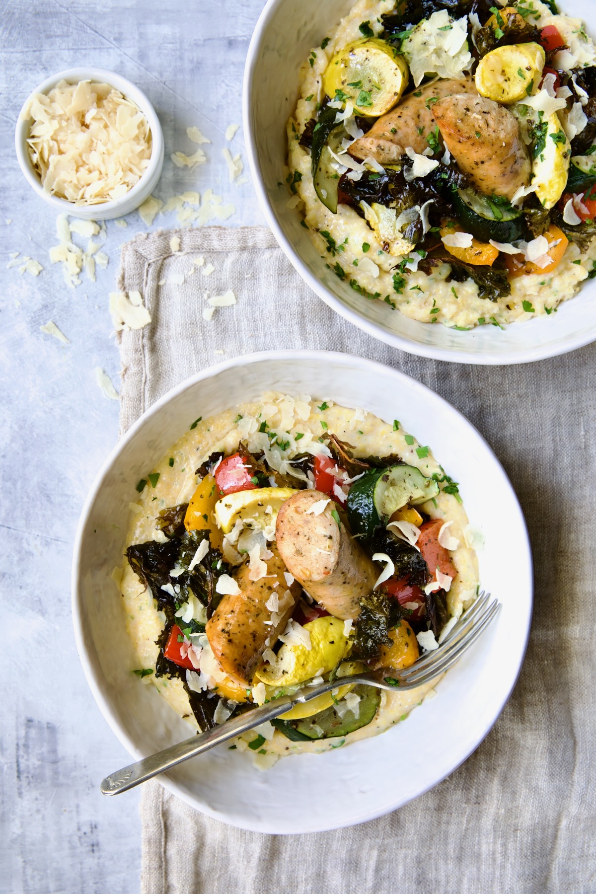 Two servings of Chicken Sausage Sheet Pan and Polenta in white bowls.