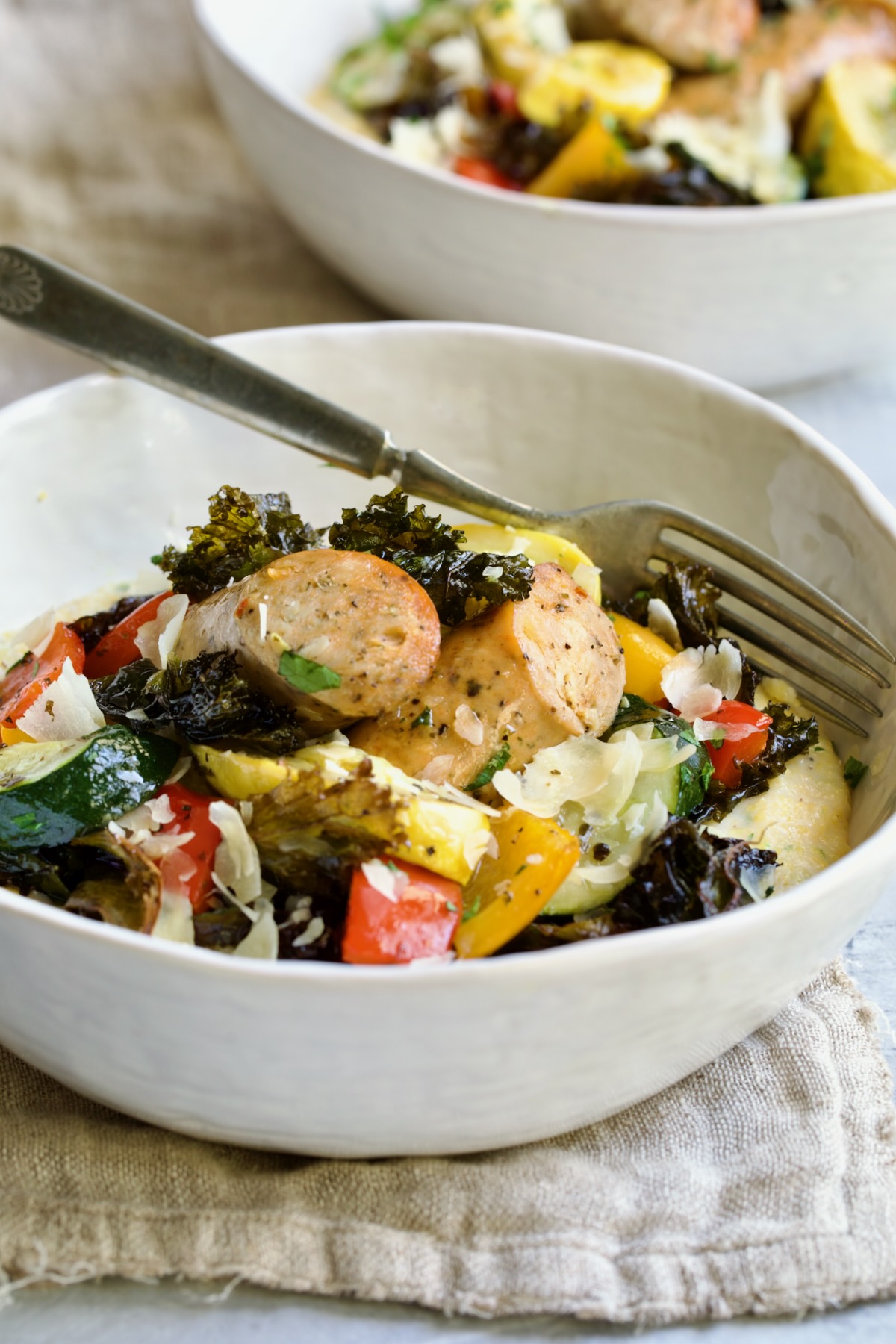 Chicken Sausage Sheet Pan and Polenta in white bowl with fork.