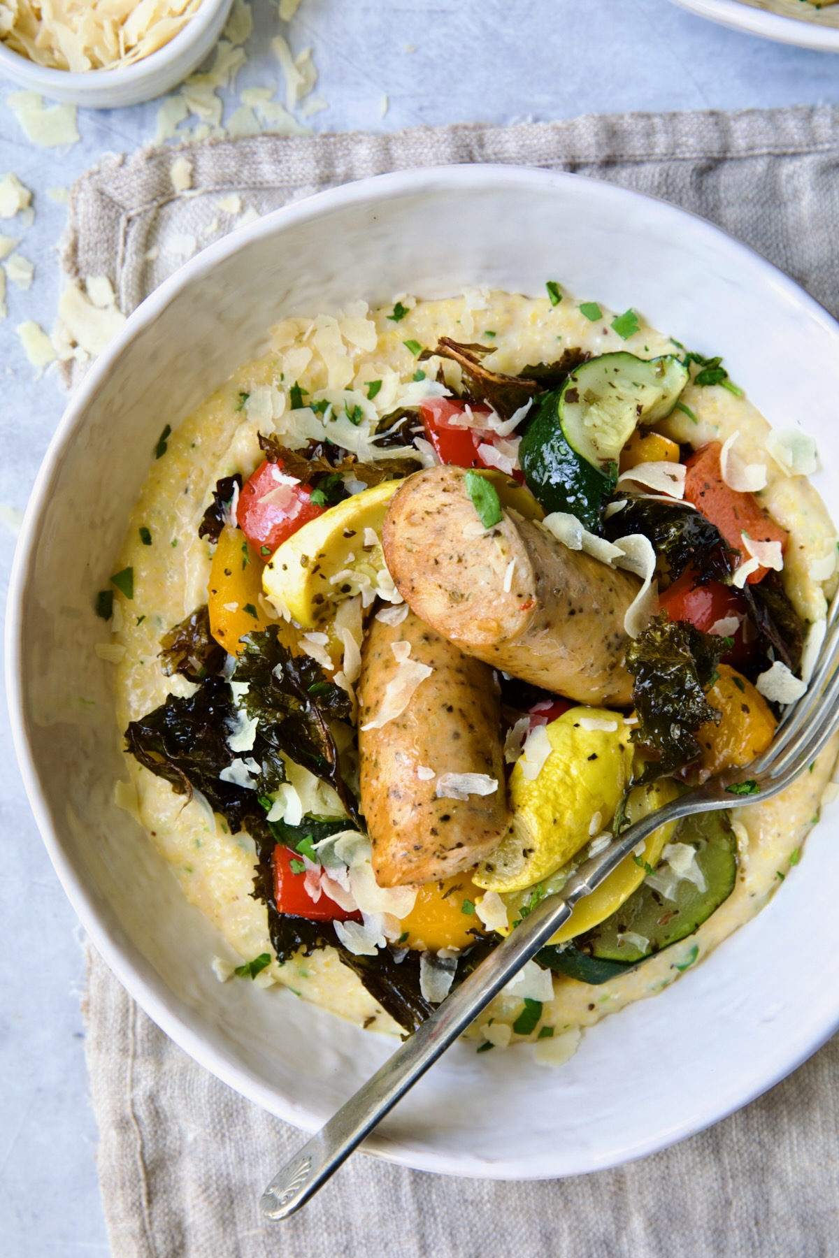 Chicken Sausage Sheet Pan and Polenta in white bowl with fork.