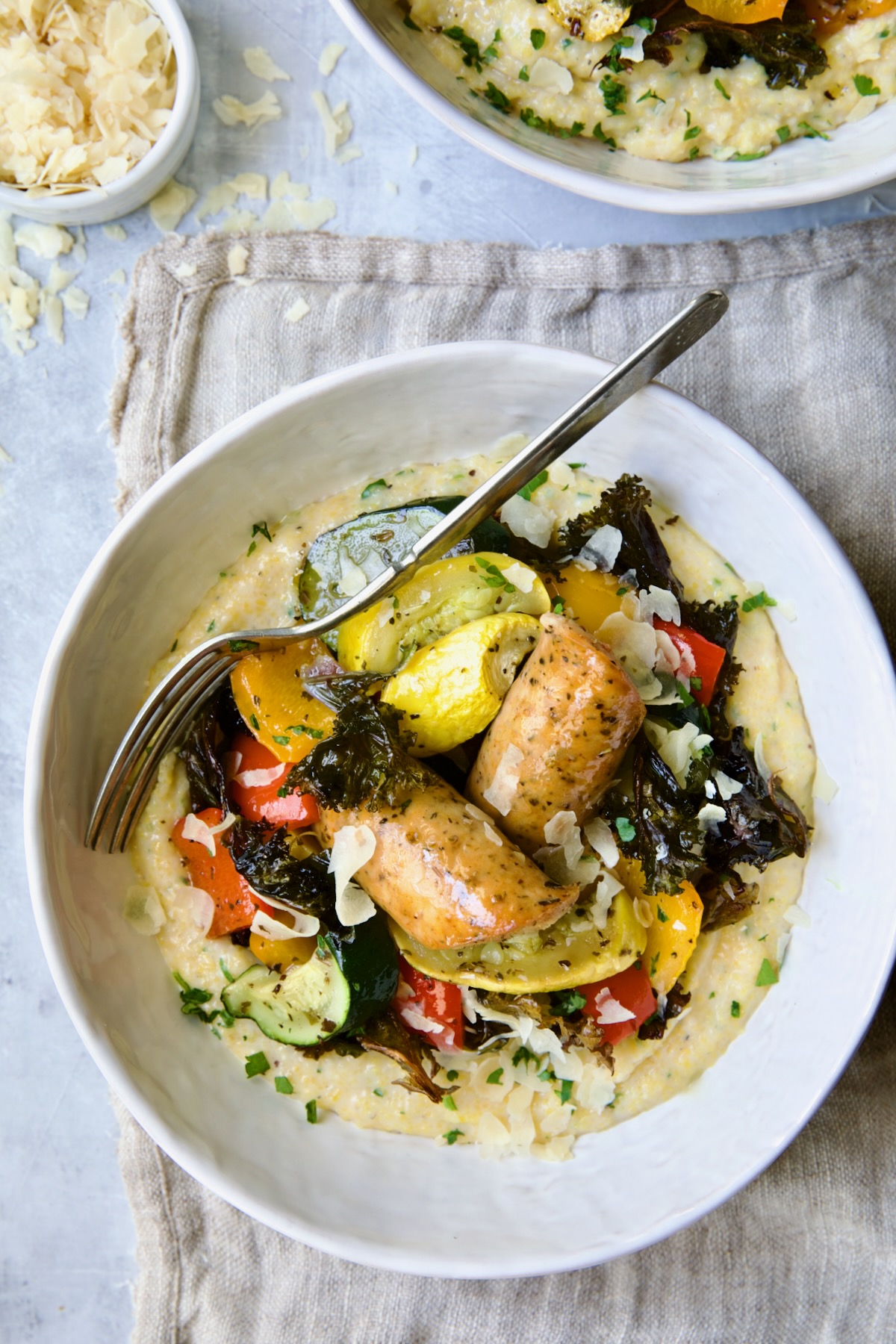 Chicken Sausage Sheet Pan and Polenta in white bowl with fork.
