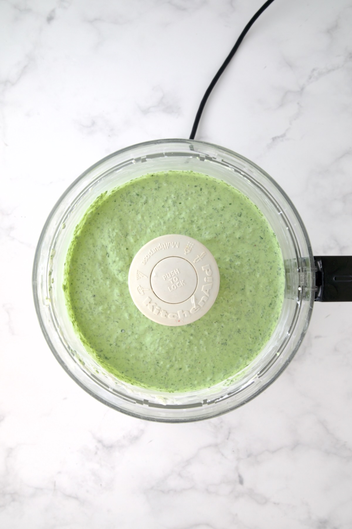 Yogurt and cream cheese in food processor with spinach added.