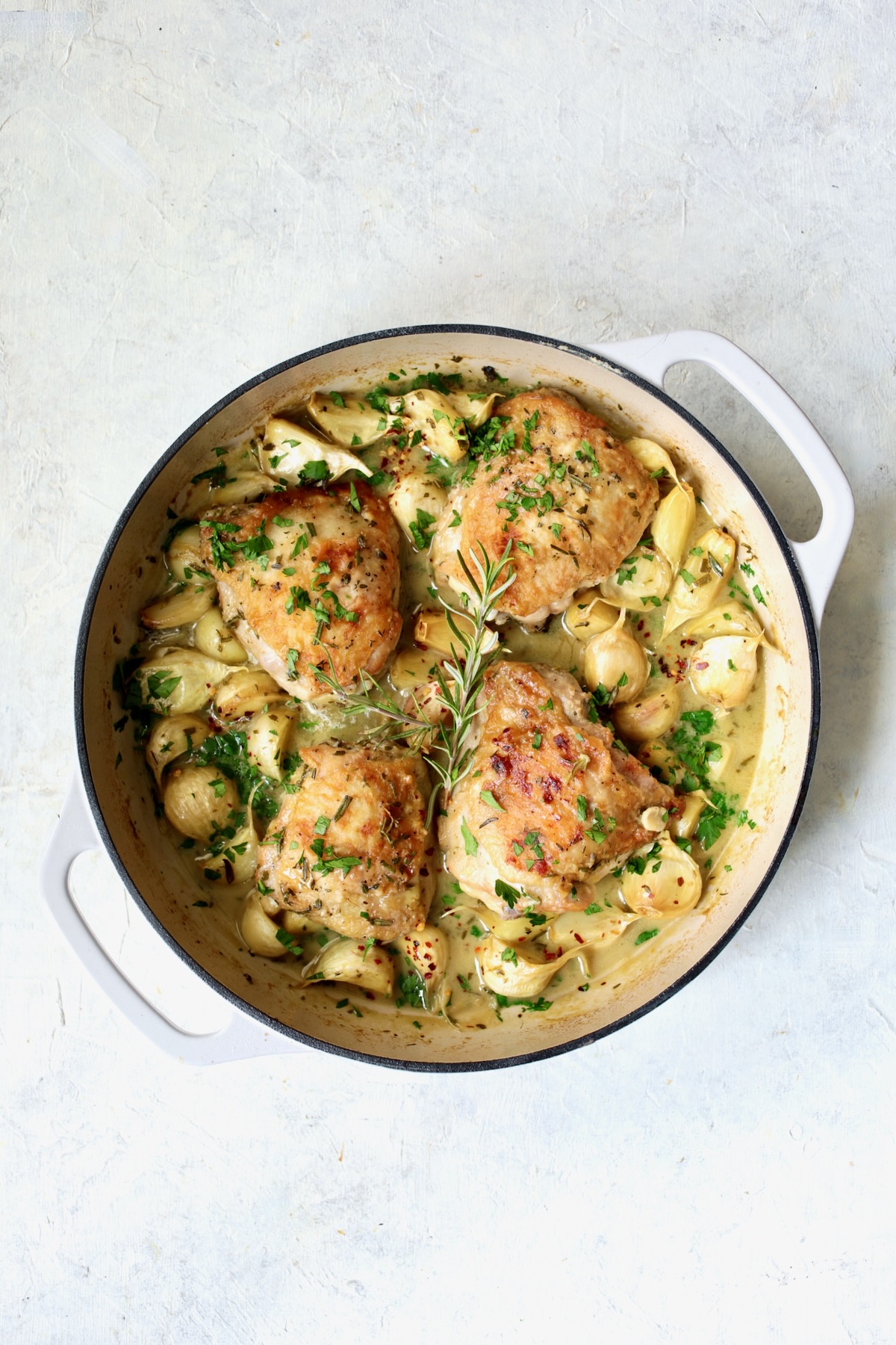 Liquid ingredients added to unpeeled garlic cloves and browned chicken thighs in white enamel cast iron skillet.