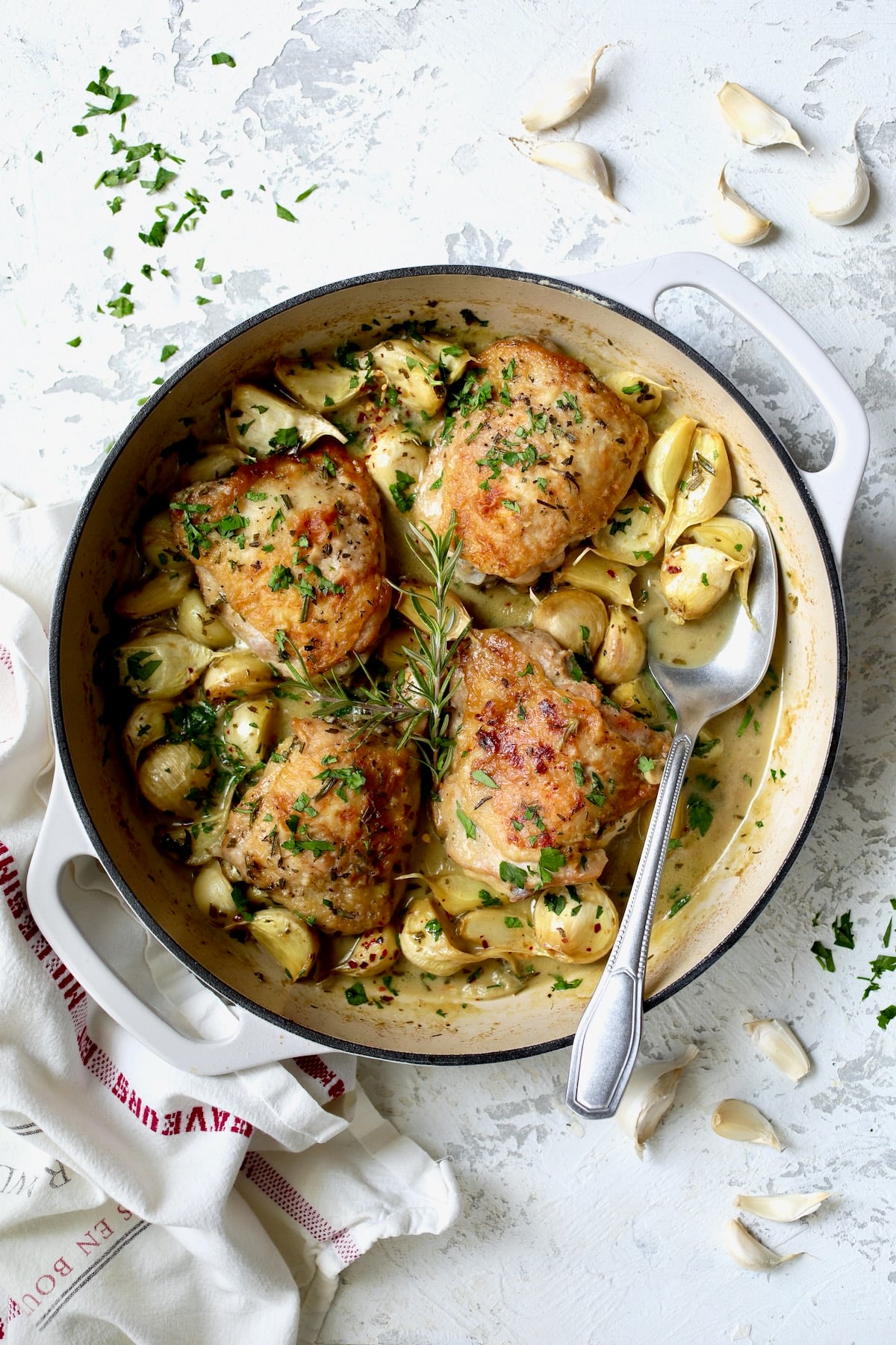 Four servings of 40 Clove Garlic Chicken in white enamel cast iron skillet.
