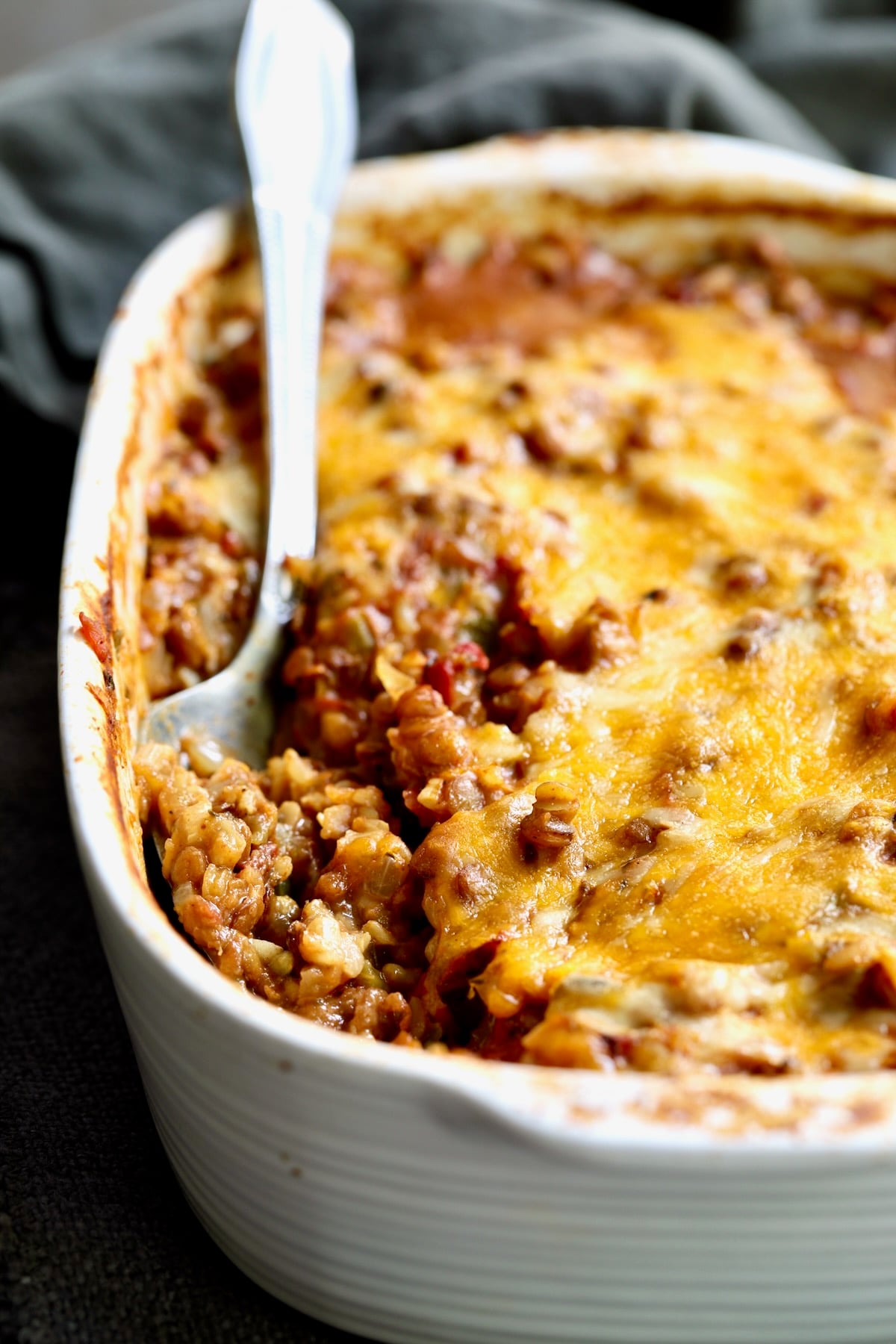 Southwestern Lentil and Brown Rice Bake in oval white baking dish with a serving removed.