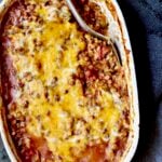 Southwestern Lentil and Brown Rice Bake in oval white baking dish with a serving removed.