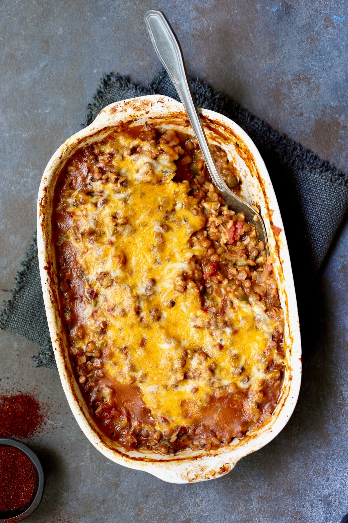 Southwestern Lentil and Brown Rice Bake in oval white baking dish with a serving removed.