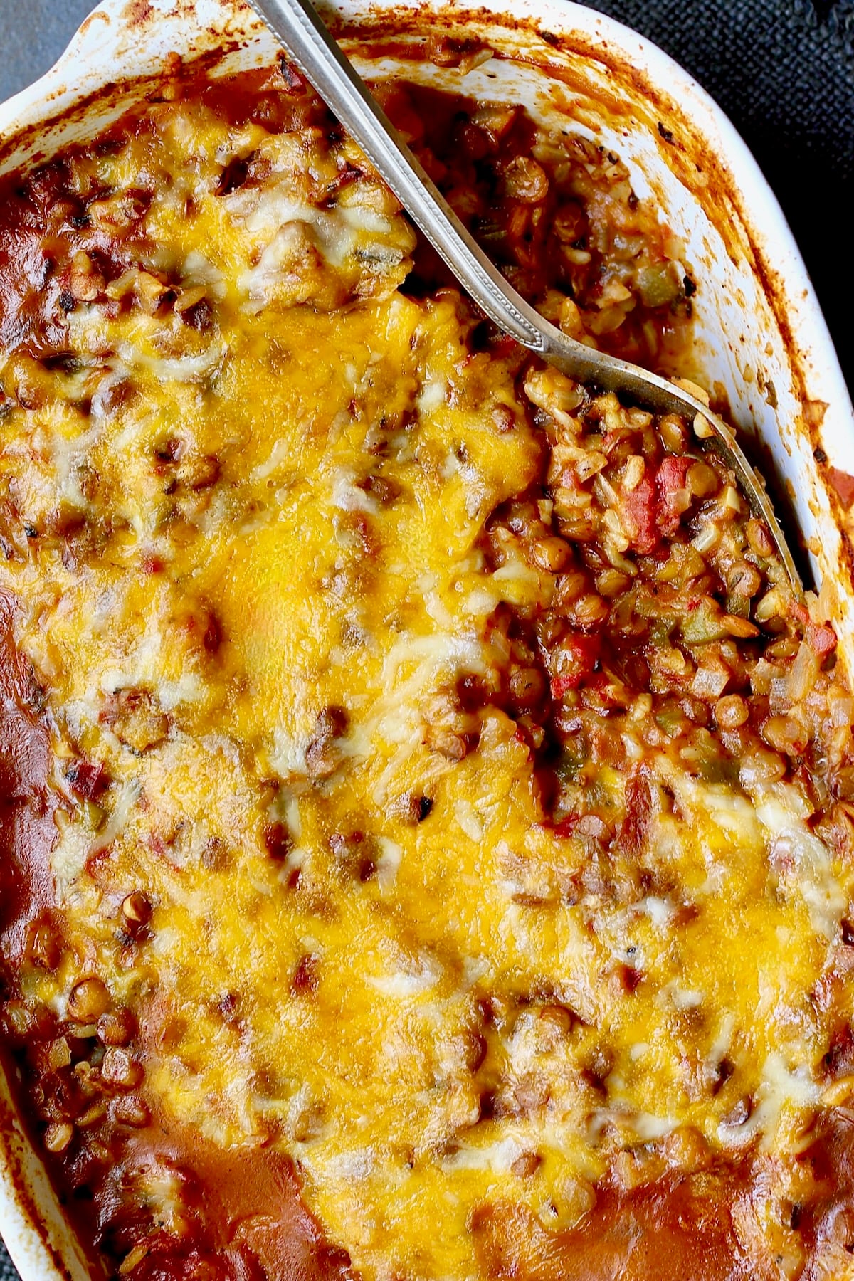 Southwestern Lentil and Brown Rice Bake in oval white baking dish with a serving removed.