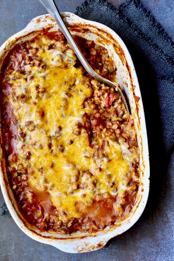 Southwestern Lentil and Brown Rice Bake in oval white baking dish with a serving removed.