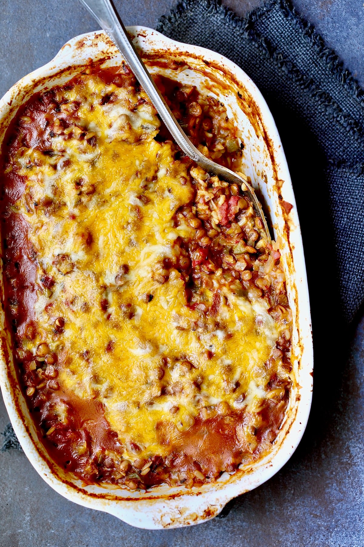 Southwestern Lentil and Brown Rice Bake in oval white baking dish with a serving removed.