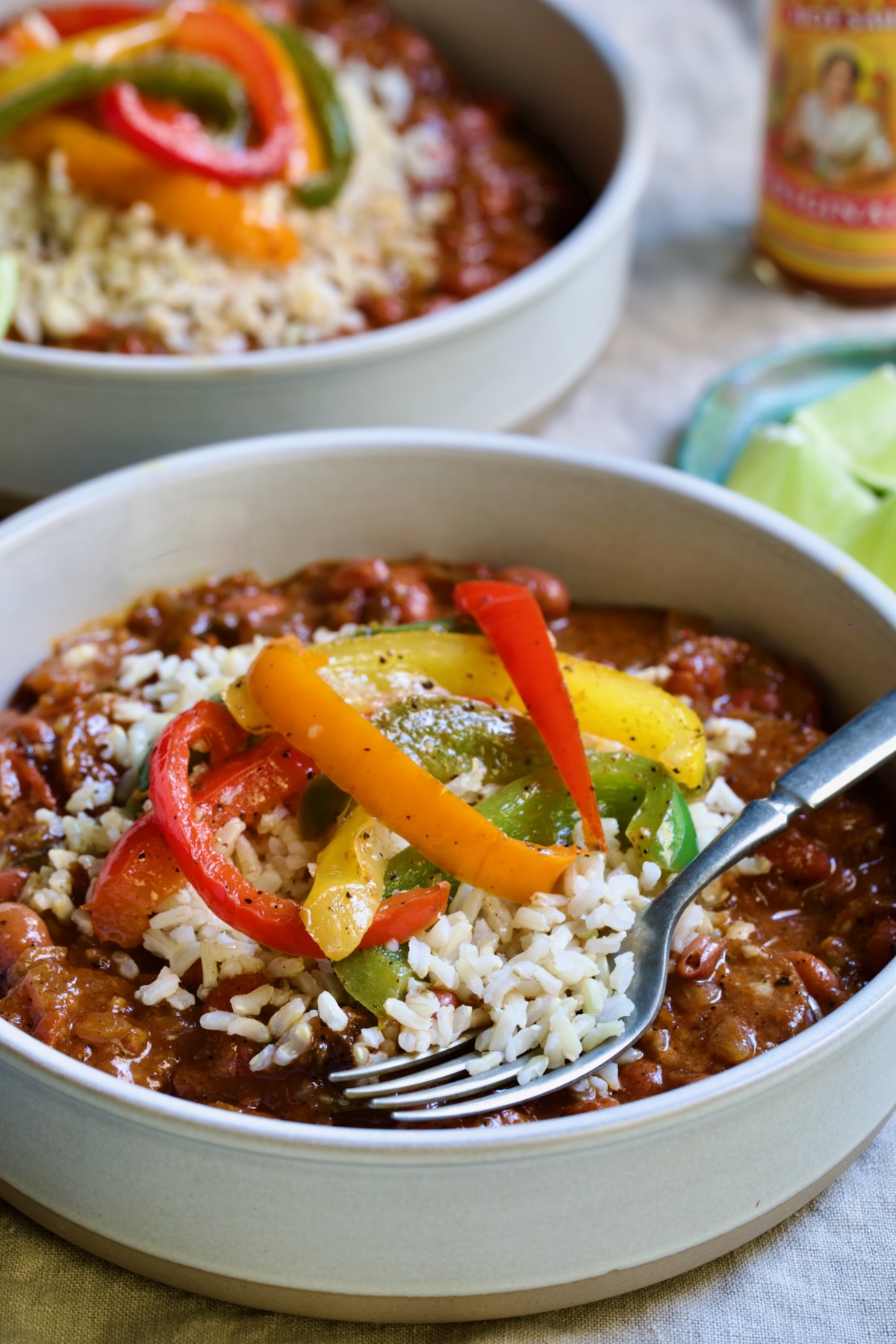 One serving of Southwestern Red Beans and Rice in a white bowl garnished with colorful sauteed bell peppers.