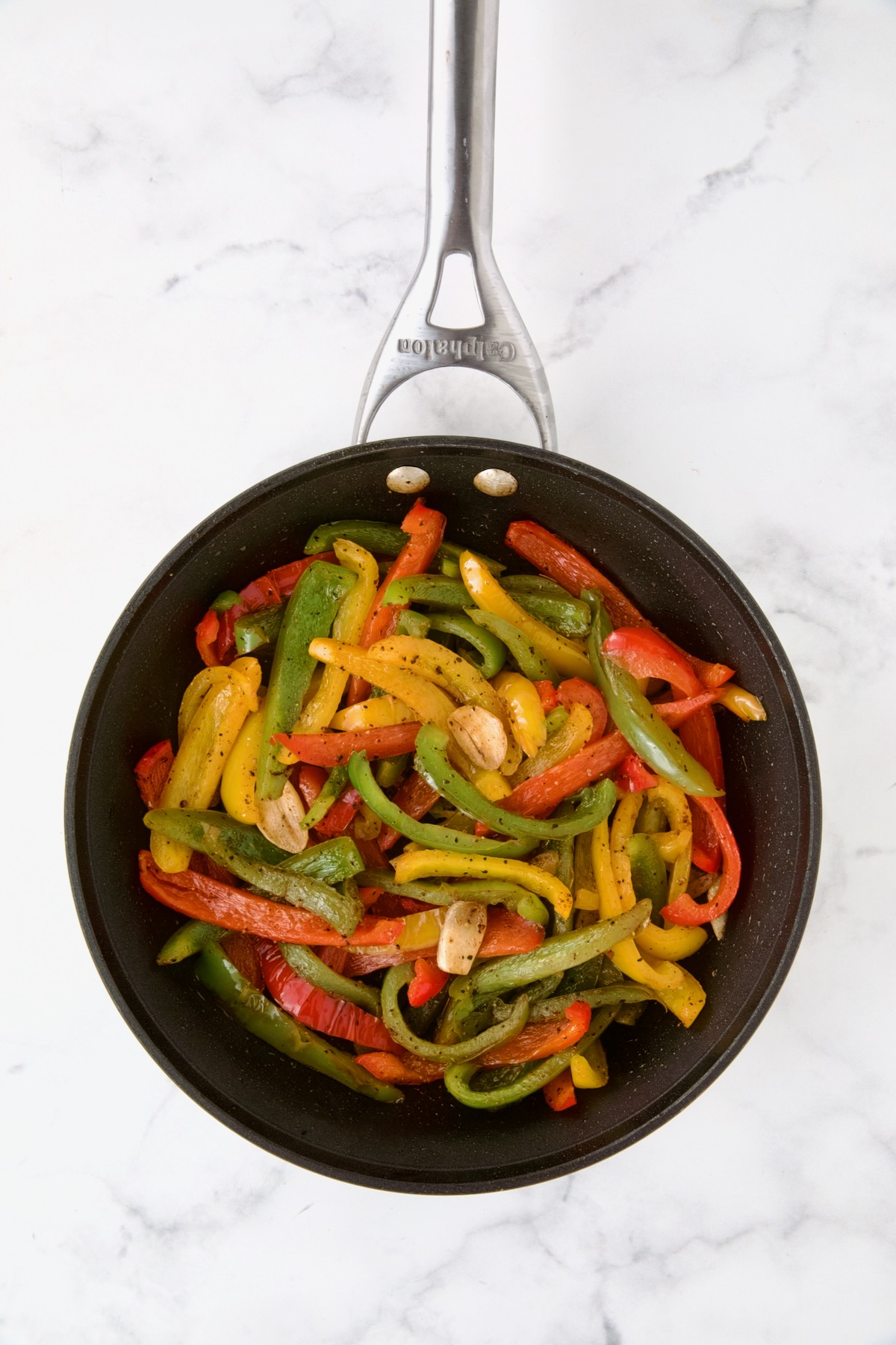 Sauteed yellow, red and green bell pepper in nonstic skillet.