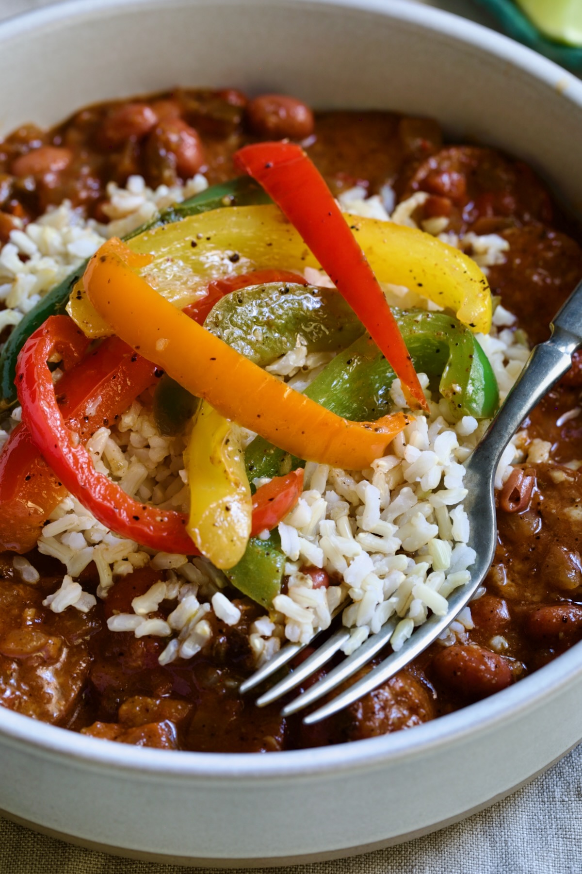 One serving of Southwestern Red Beans and Rice in white bowls garnished with colorful sauteed bell peppers.