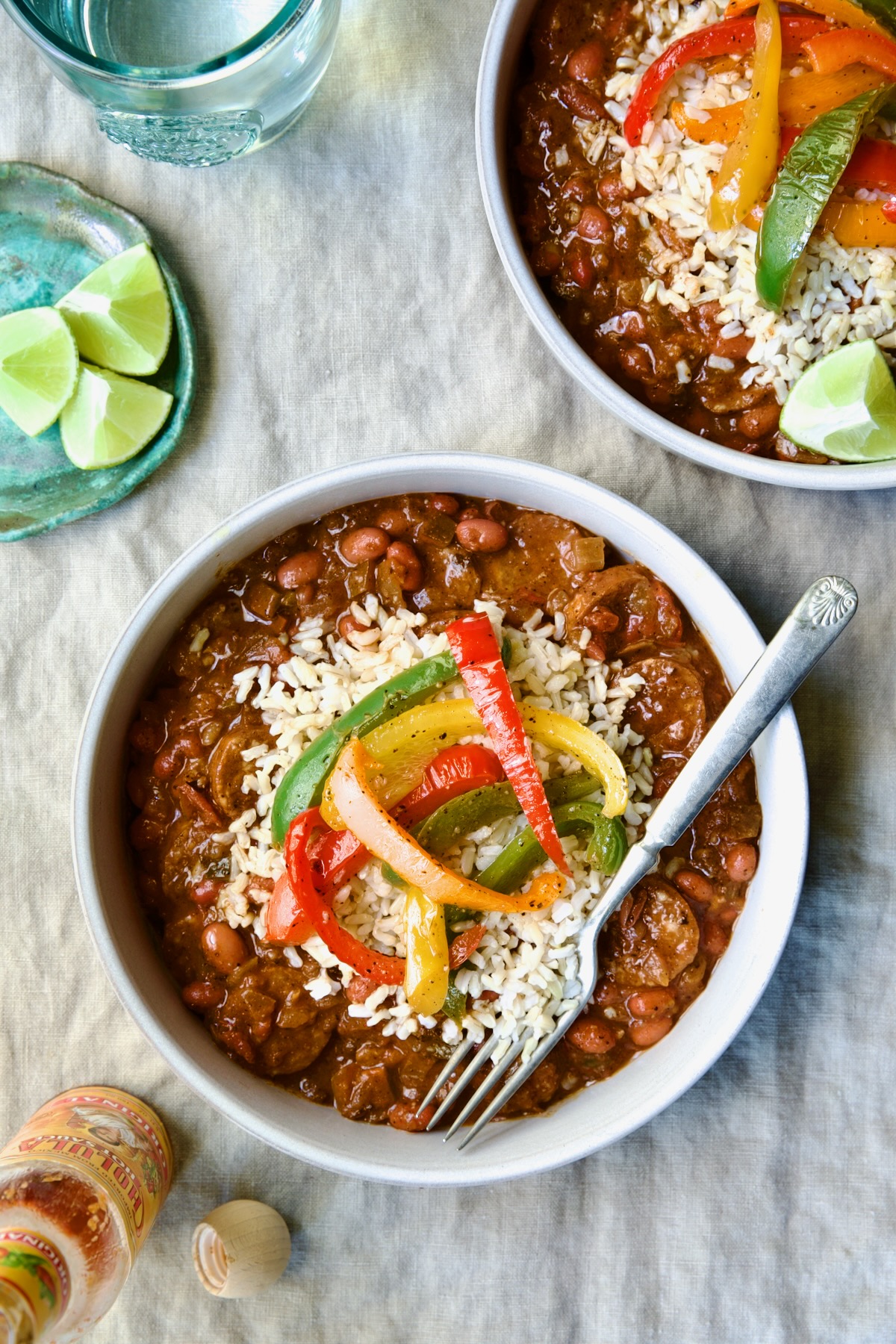Two servings of Southwestern Red Beans and Rice in white bowls garnished with colorful sauteed bell peppers.