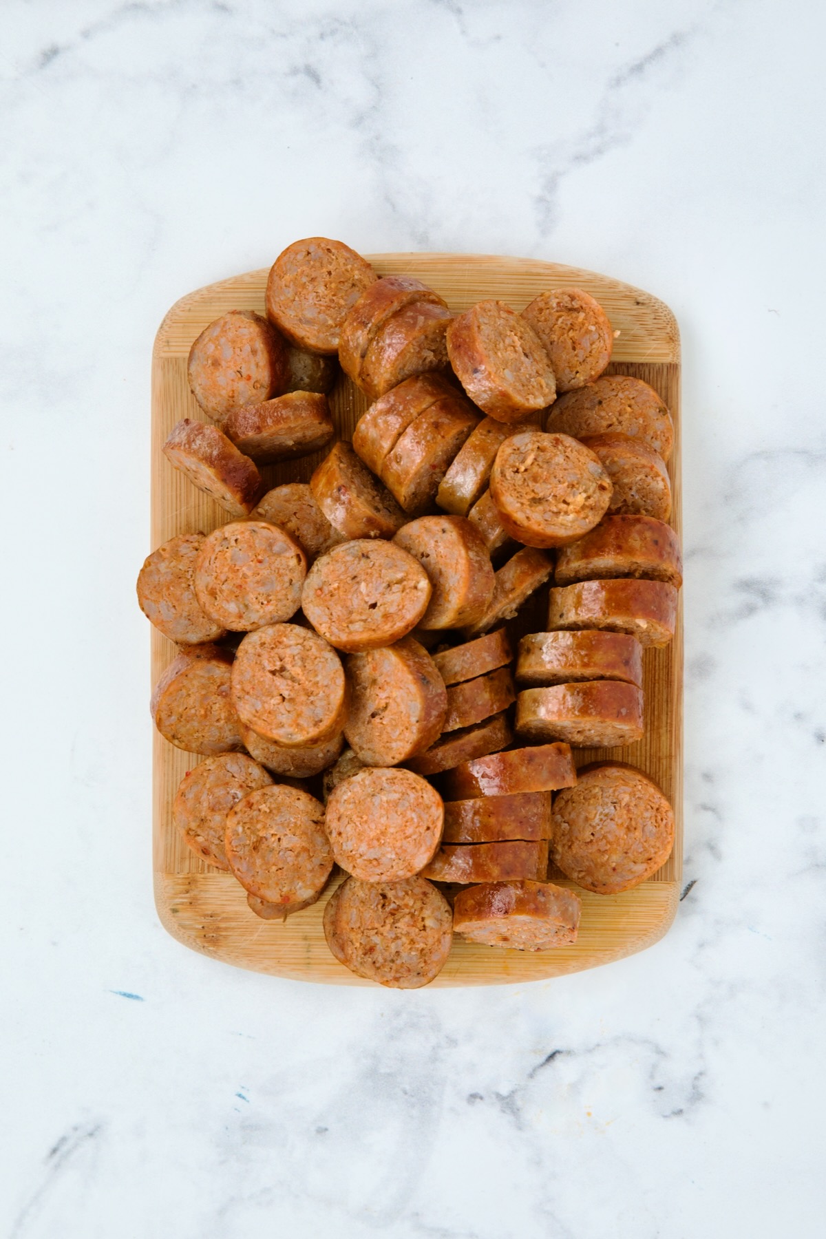 Sliced cooked chorizo sausage on wooden cutting board.