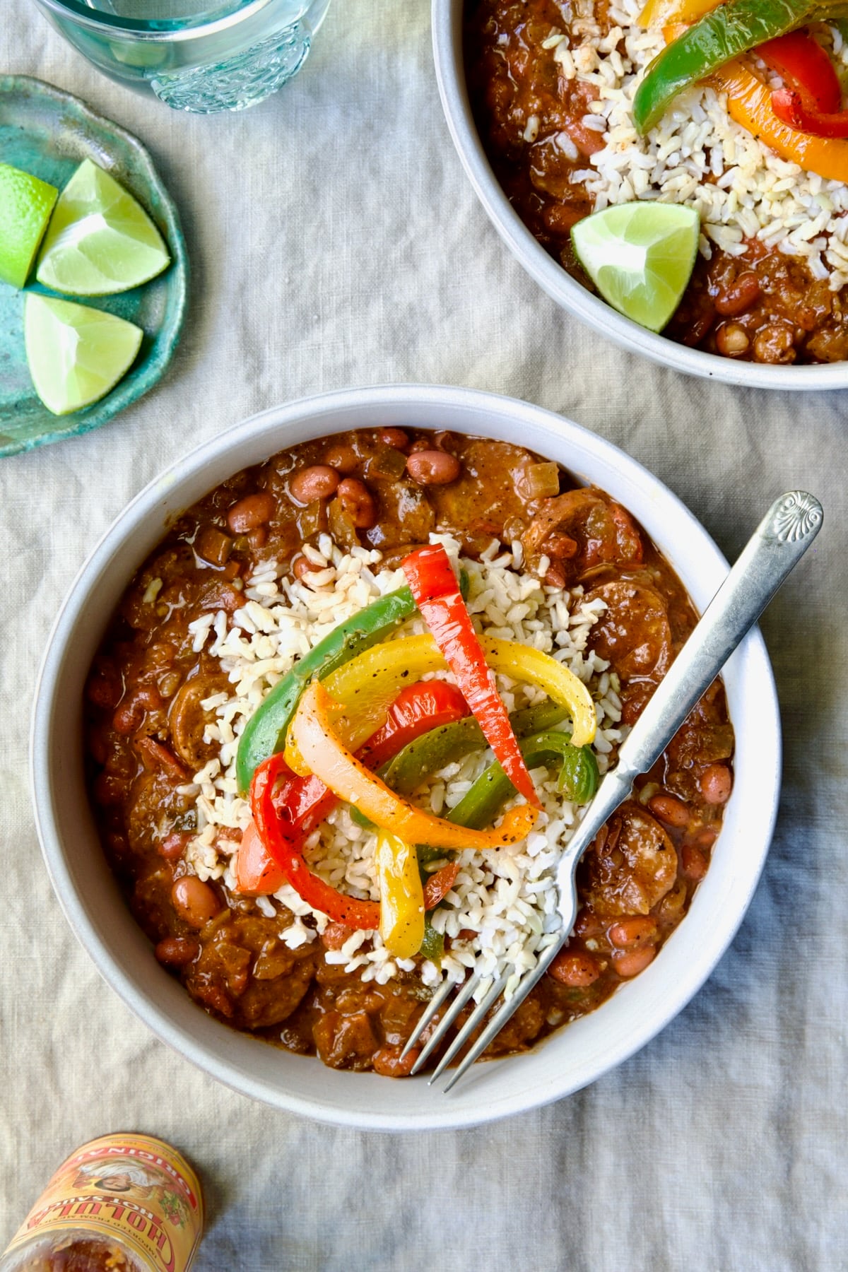 Two servings of Southwestern Red Beans and Rice in white bowls garnished with colorful sauteed bell peppers.