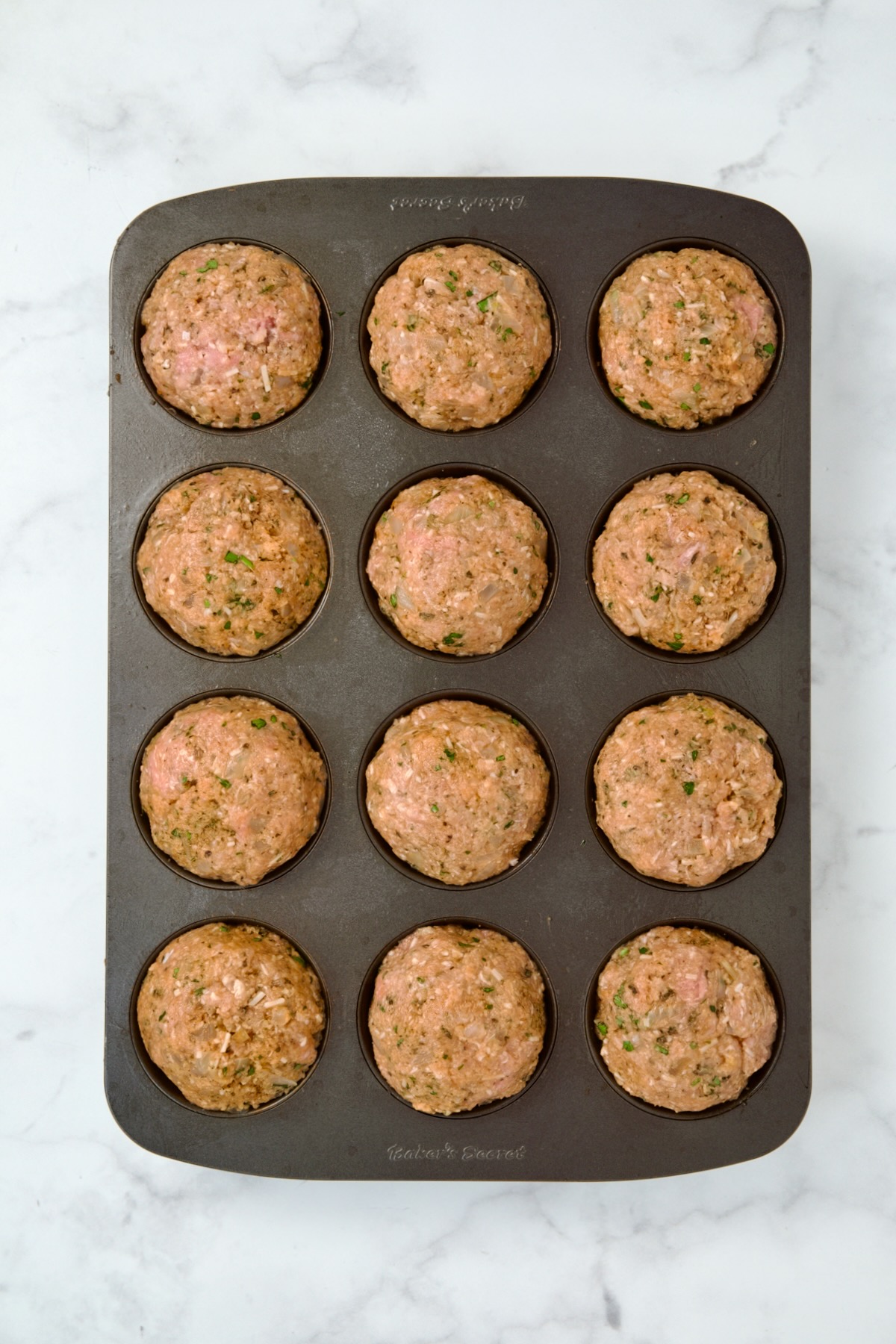 Uncooked Turkey Meatloaf Muffins in 12-cup muffin pan.