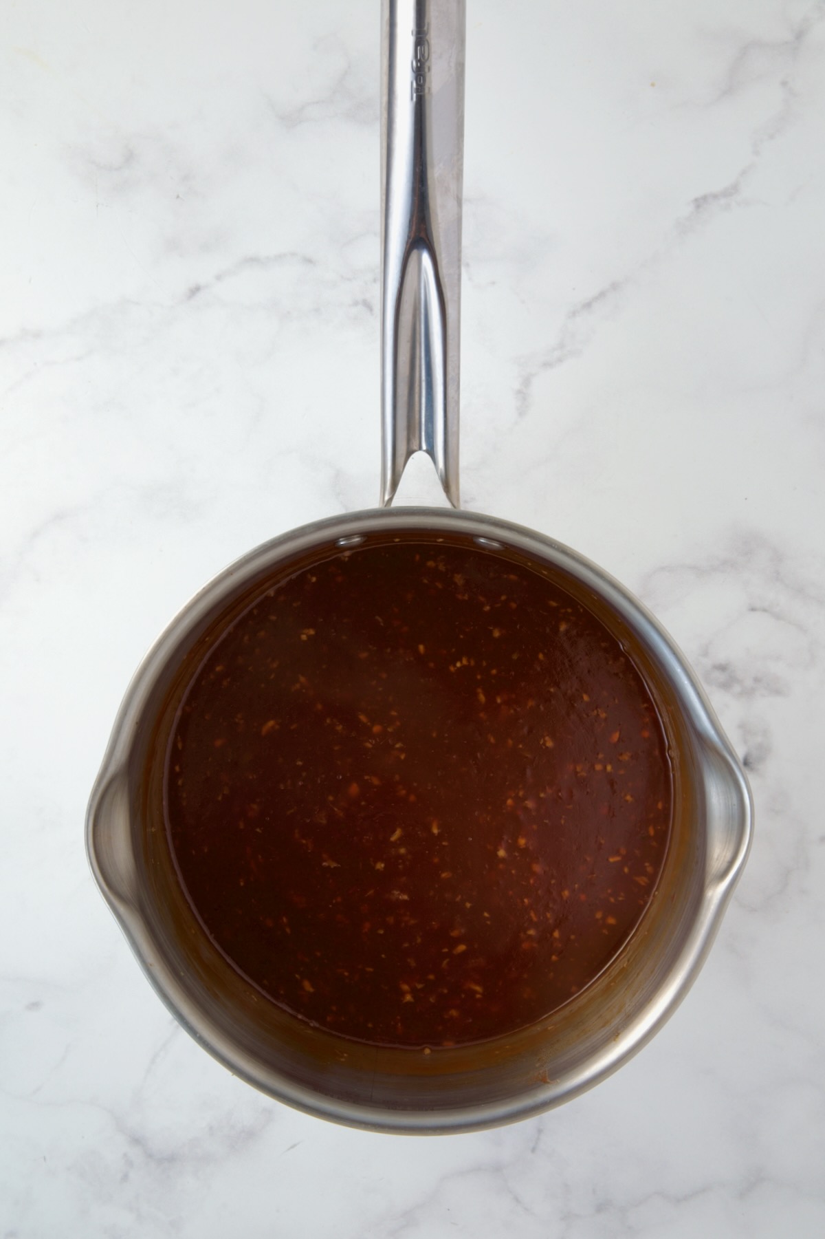 Sauce for meatballs in stainless steel saucepan.