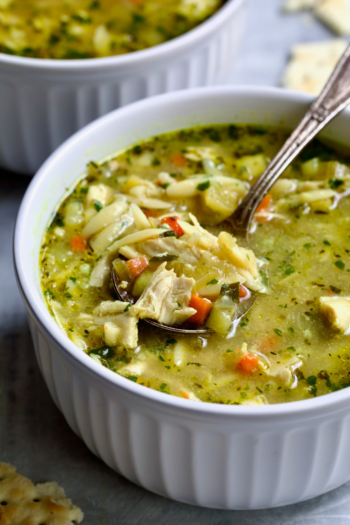 One serving of Chicken Vegetable Soup with Orzo in white bowl.