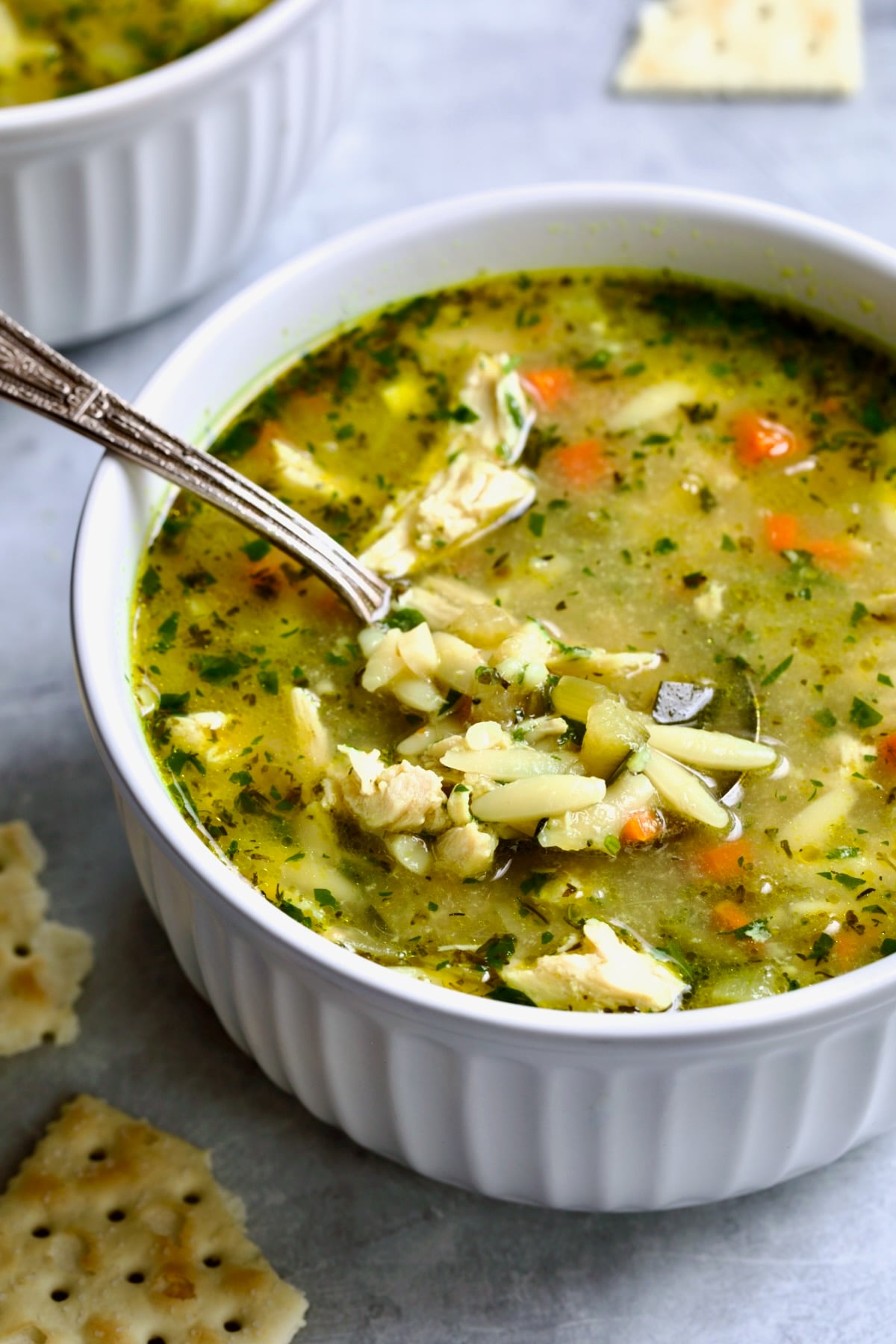 One serving of Chicken Vegetable Soup with Orzo in white bowl.