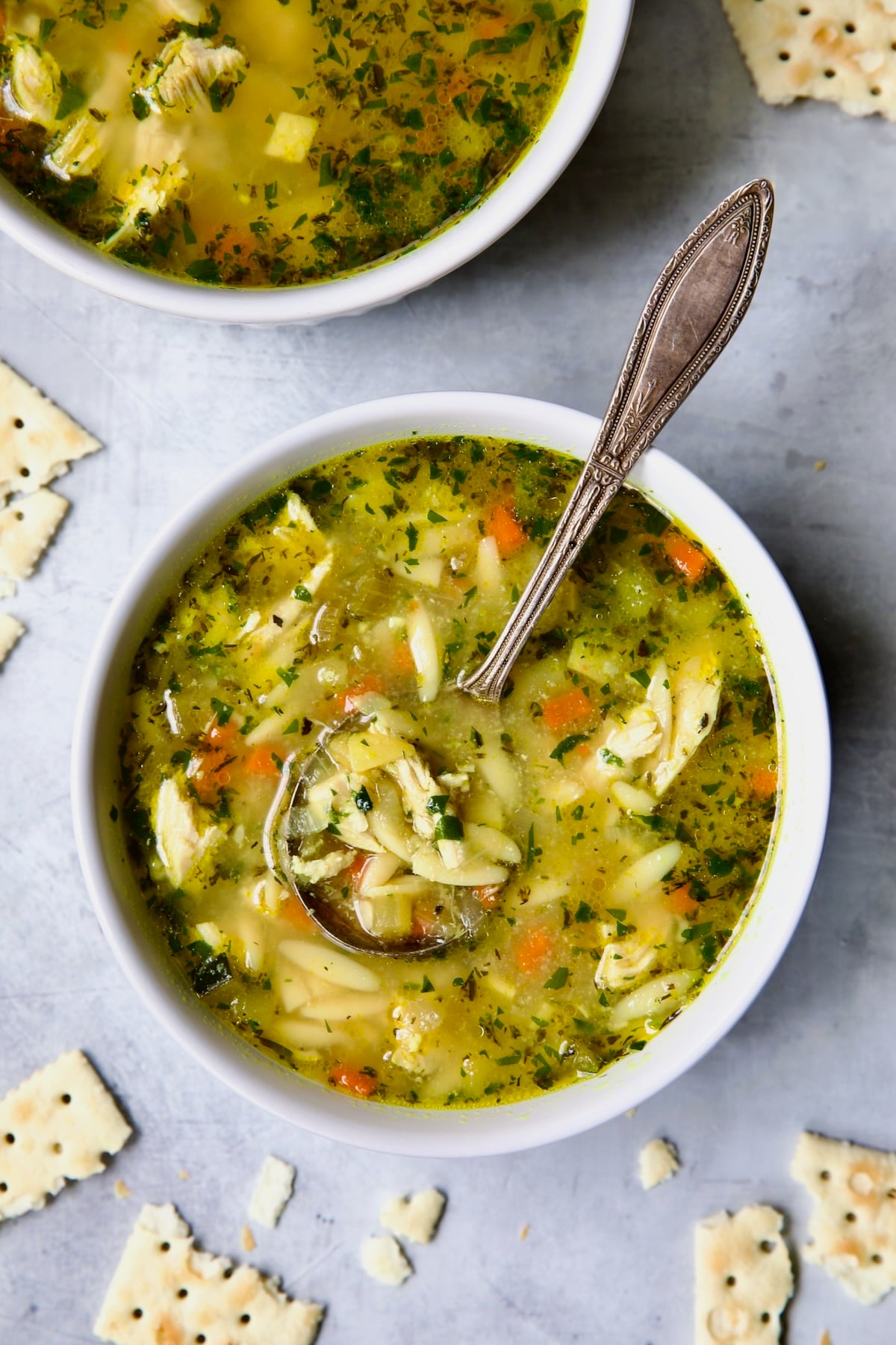 One serving of Chicken Vegetable Soup with Orzo in white bowl.