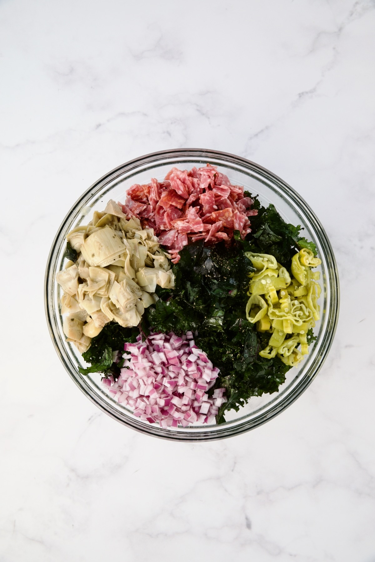 Ingredients for kale salad in glass bowl before being combined.