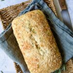 Loaf of Easy Herb Bread on blue napkin in wicker basket.
