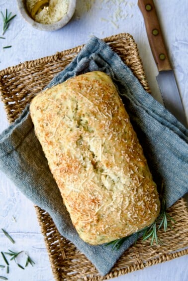 Loaf of Easy Herb Bread on blue napkin in wicker basket.