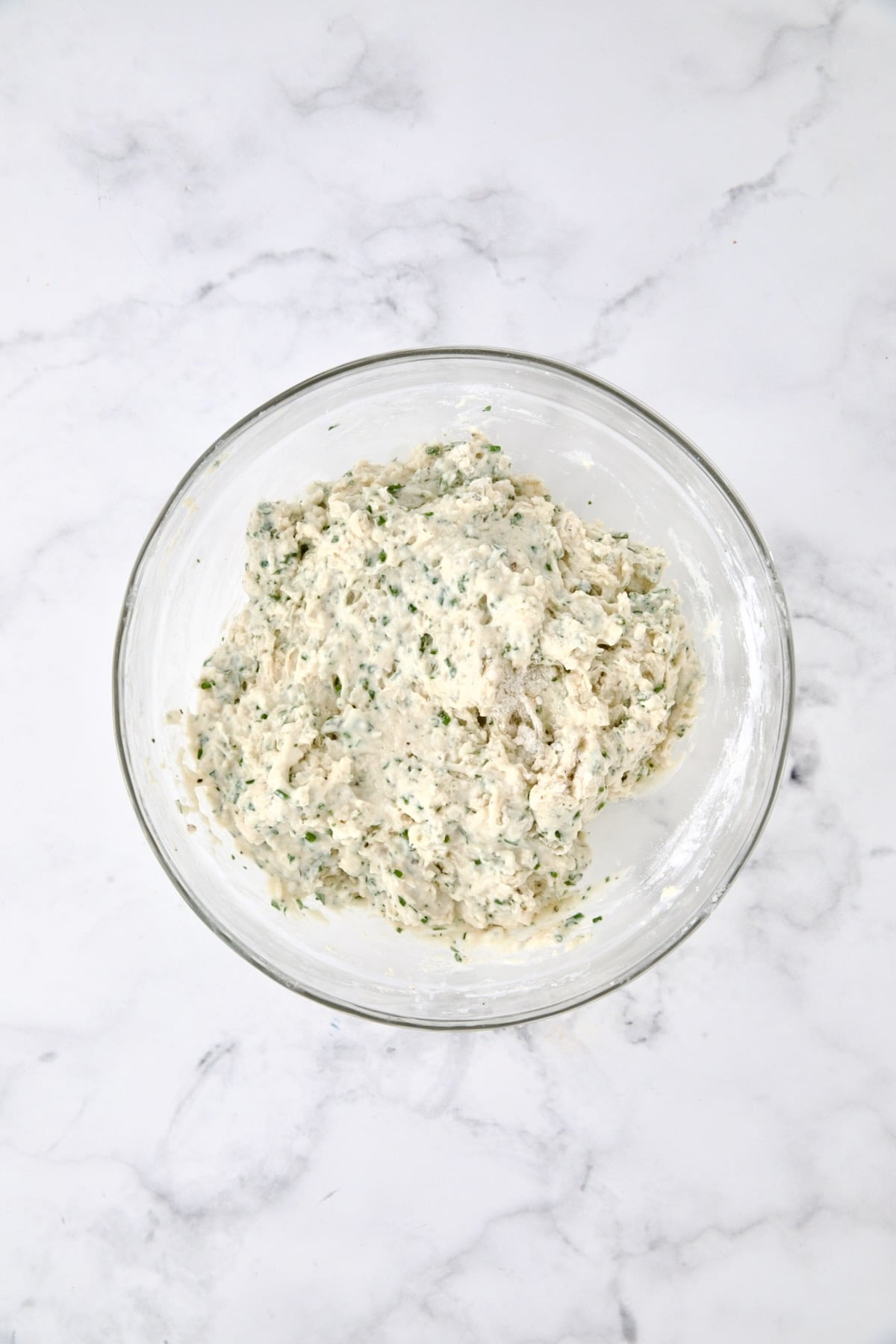 Wet and dry ingredients for bread combined in glass bowl.