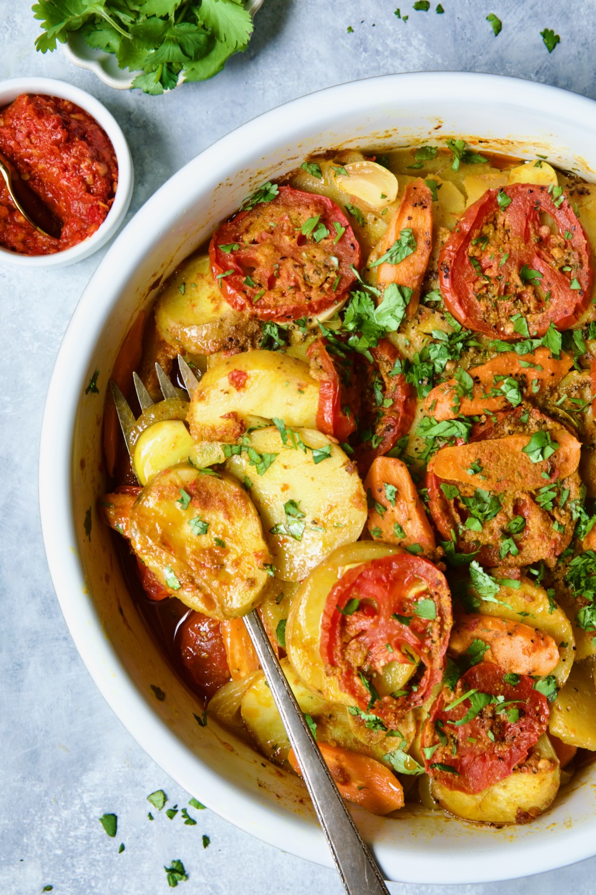 Moroccan Potato Tagine in round white baking dish with serving fork.
