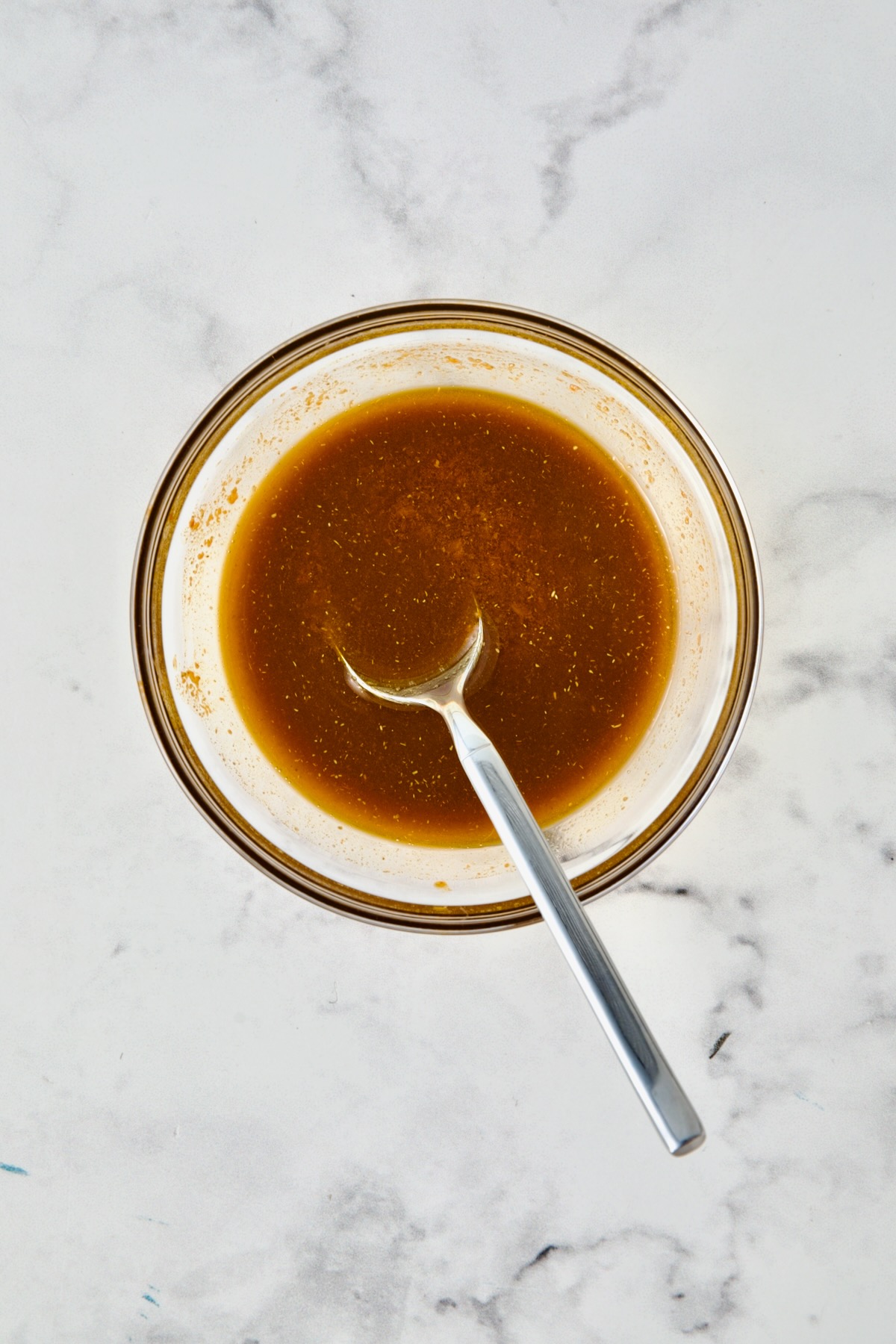 Olive oil and spices blended together in glass bowl.