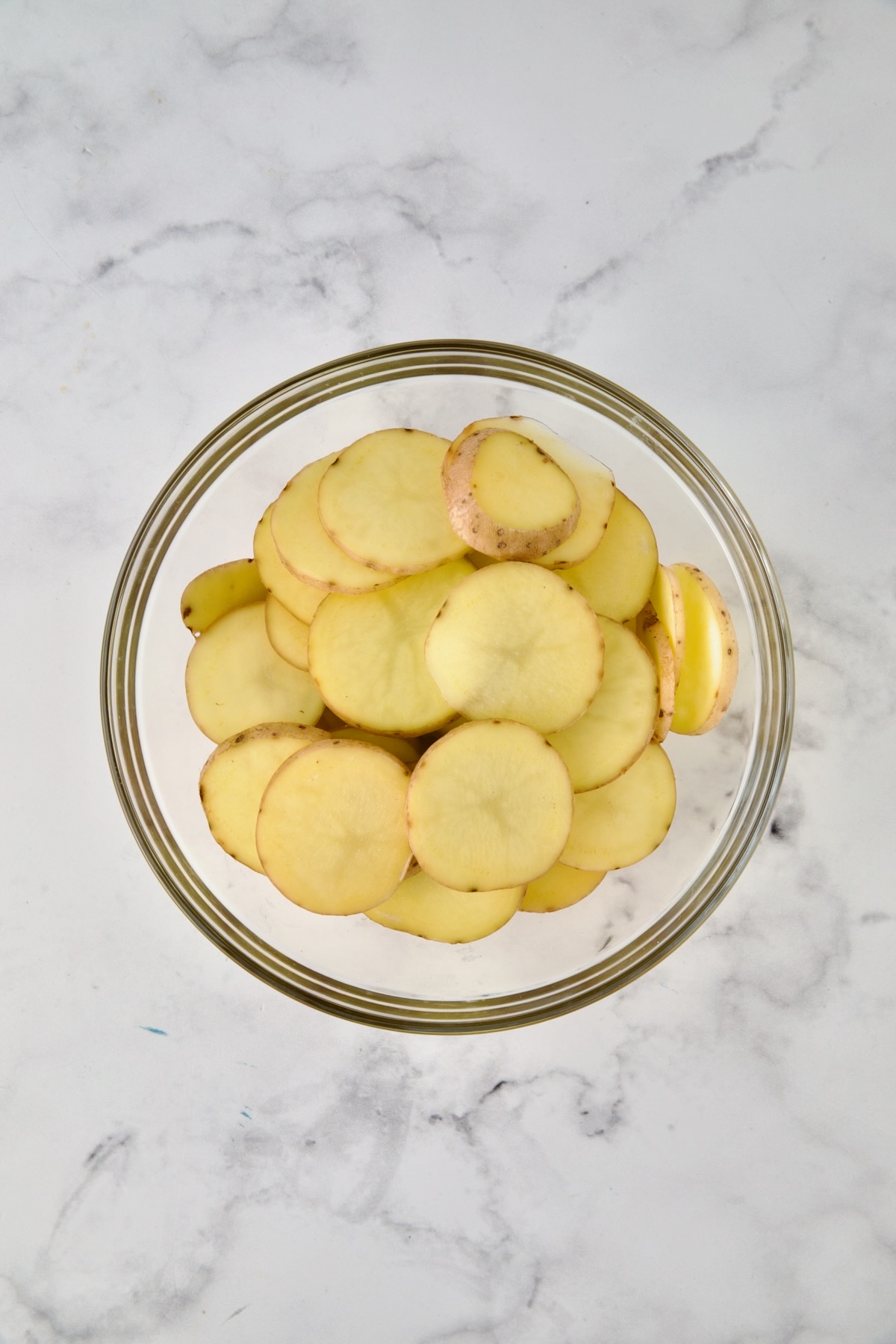 Sliced potatoes in glass bowl.