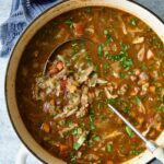 Beef and Cabbage Soup in white Dutch oven with soup ladle.