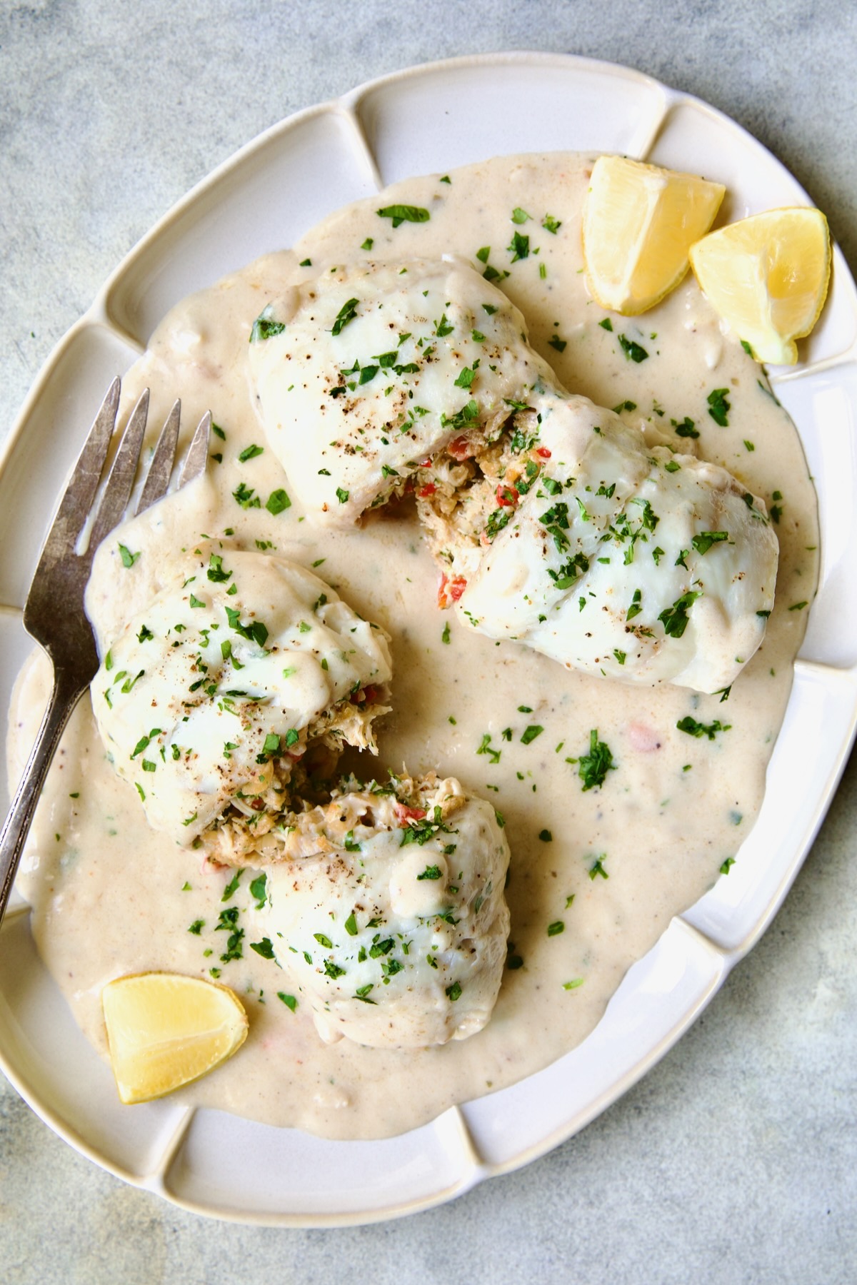 Two servings of Crab-Stuffed Flounder on oval platter with lemon wedges cut open to expose filling.