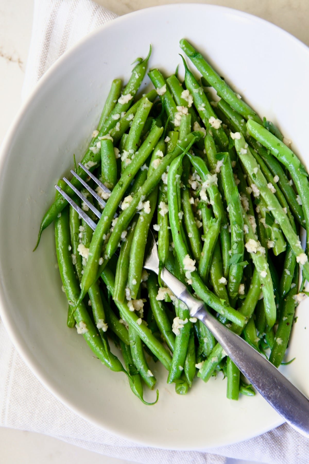 Garlic Green Beans in oval white serving bowl with serving fork.