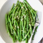Garlic Green Beans in oval white serving bowl with serving fork.