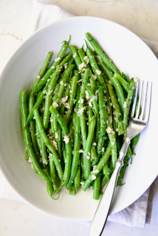Garlic Green Beans in oval white serving bowl with serving fork.