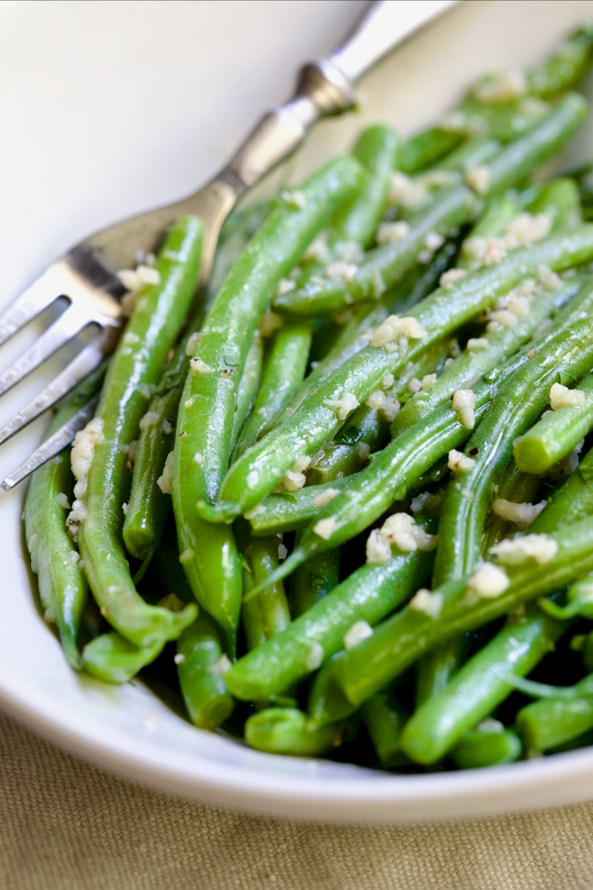 Garlic Green Beans in oval white serving bowl with serving fork.