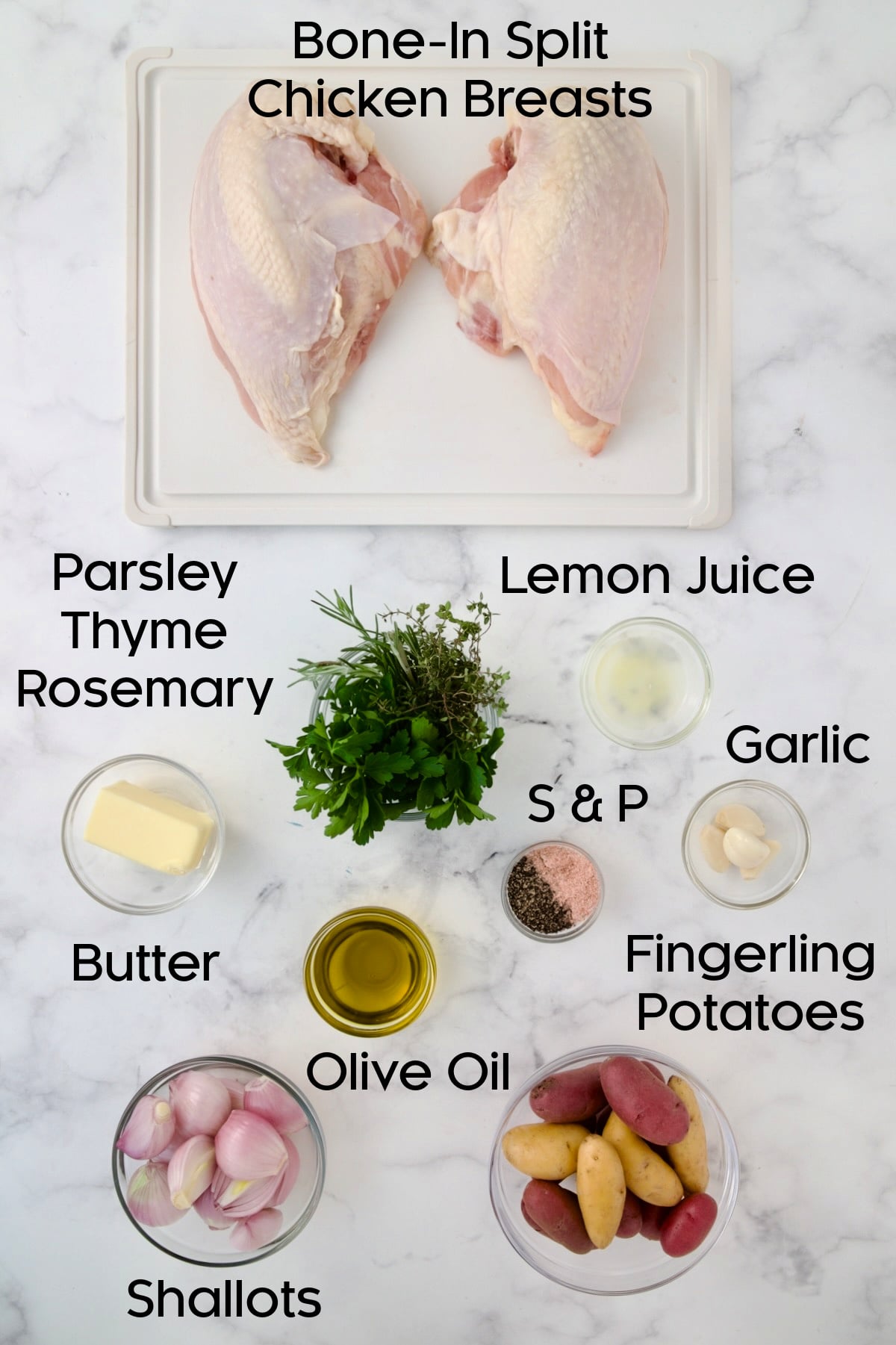 Ingredients for Roast Split Chicken Breasts with Potatoes and Shallots with chicken on a white plastic cutting board and the rest in glass bowls.