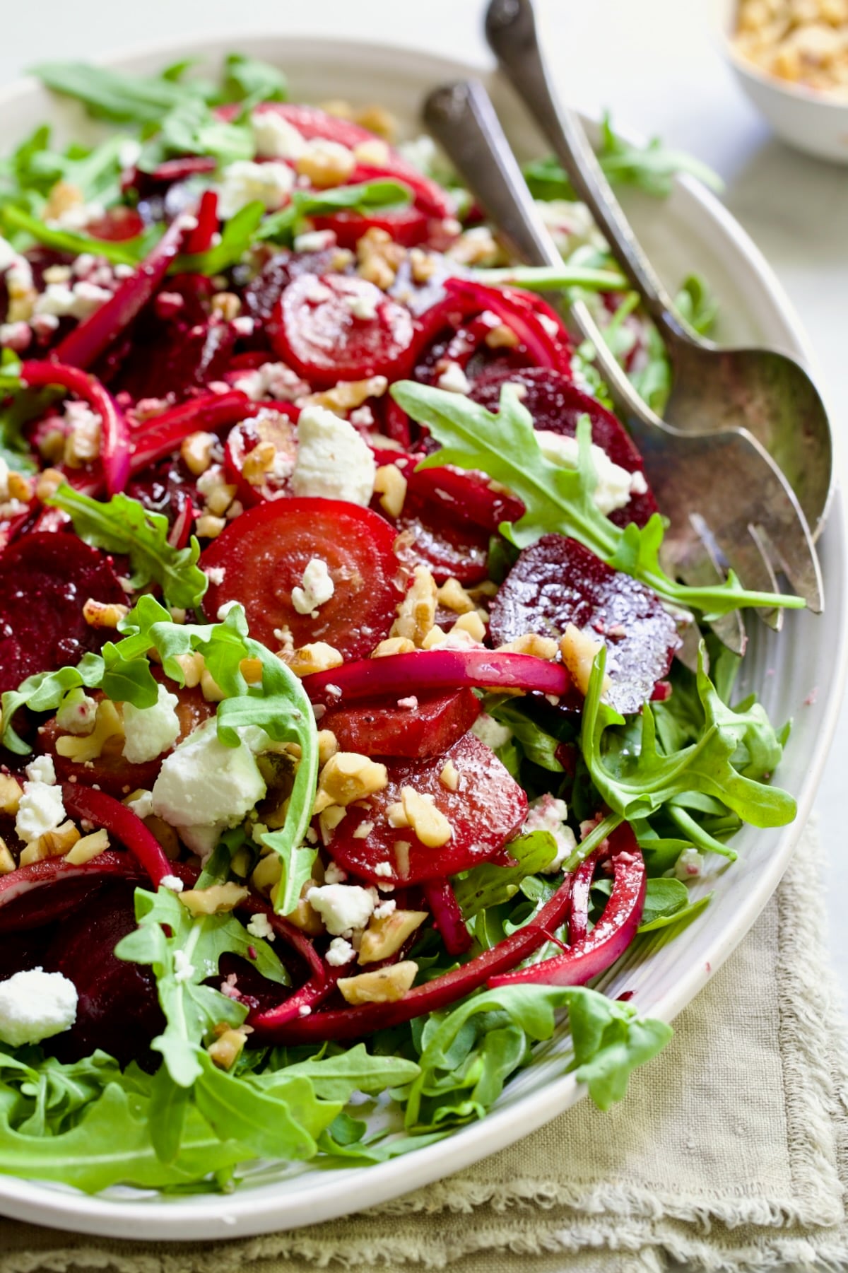 Roasted Beet Salad on oval white platter with serving utensils.