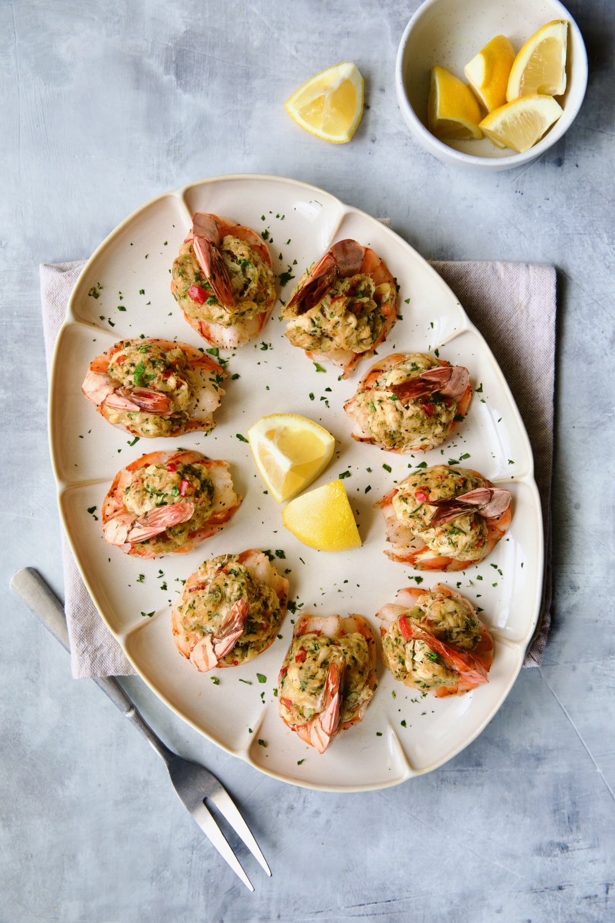 Crab-Stuffed Shrimp on oval white platter garnished with parsley and lemon wedges.
