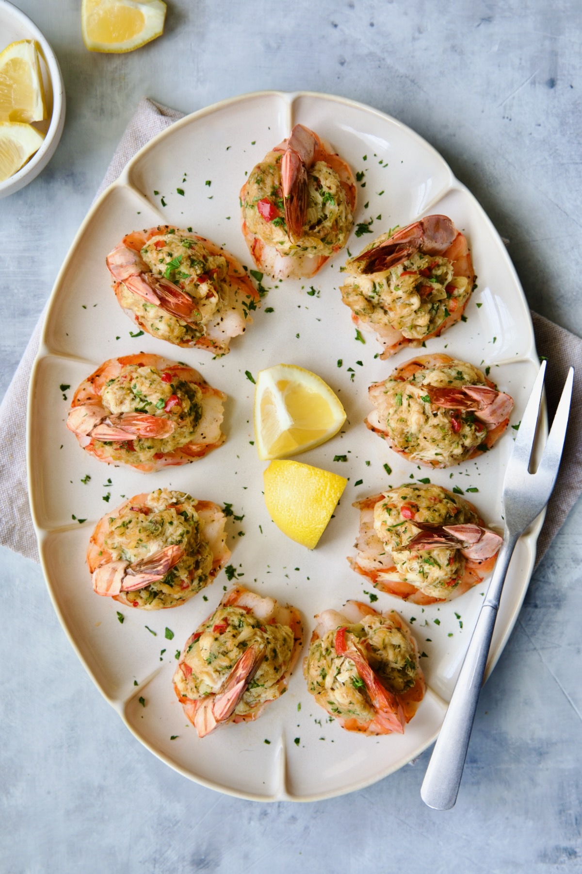 Crab-Stuffed Shrimp on oval white platter garnished with parsley and lemon wedges.