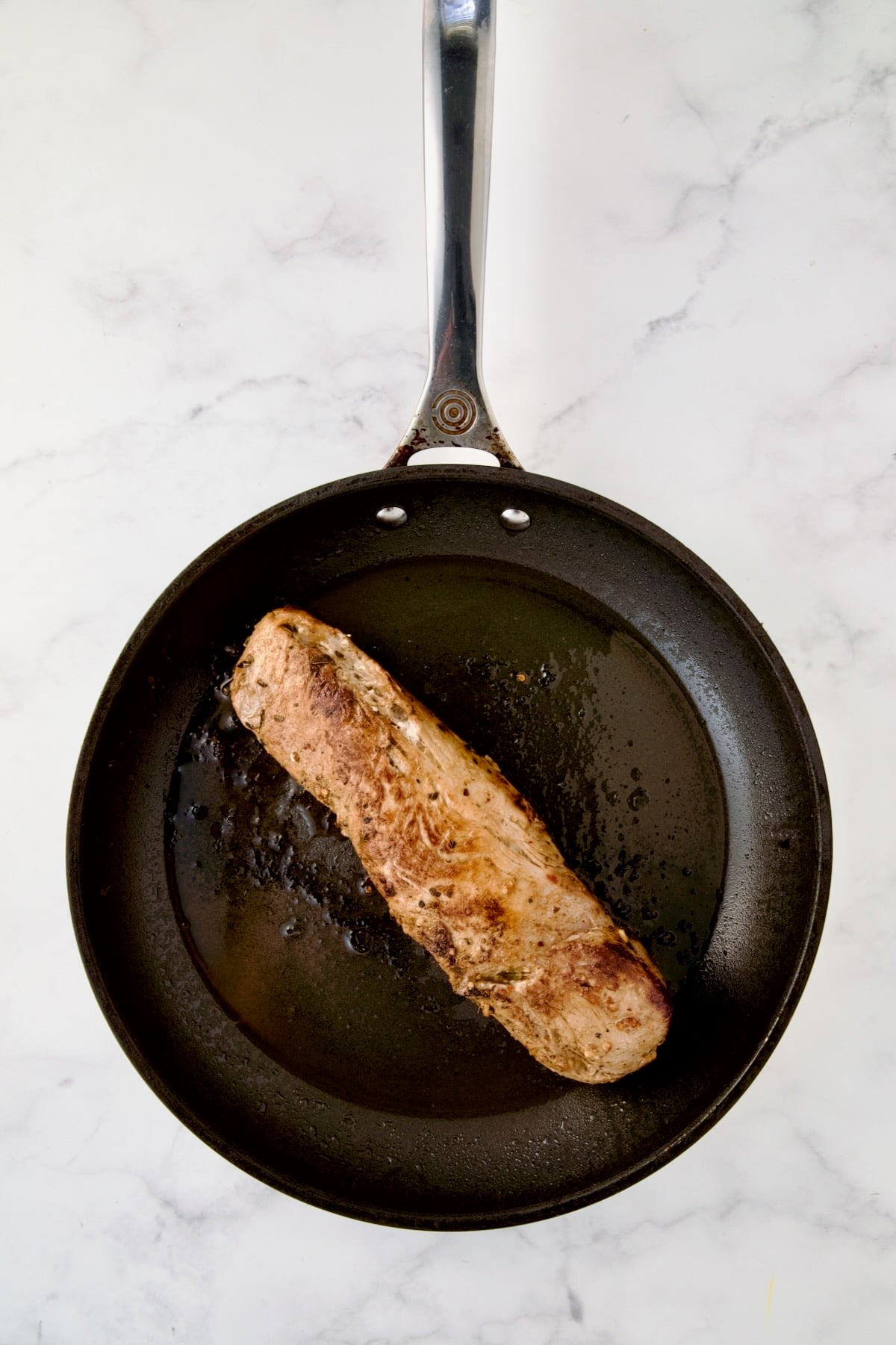 Seared pork tenderloin in nonstick skillet.