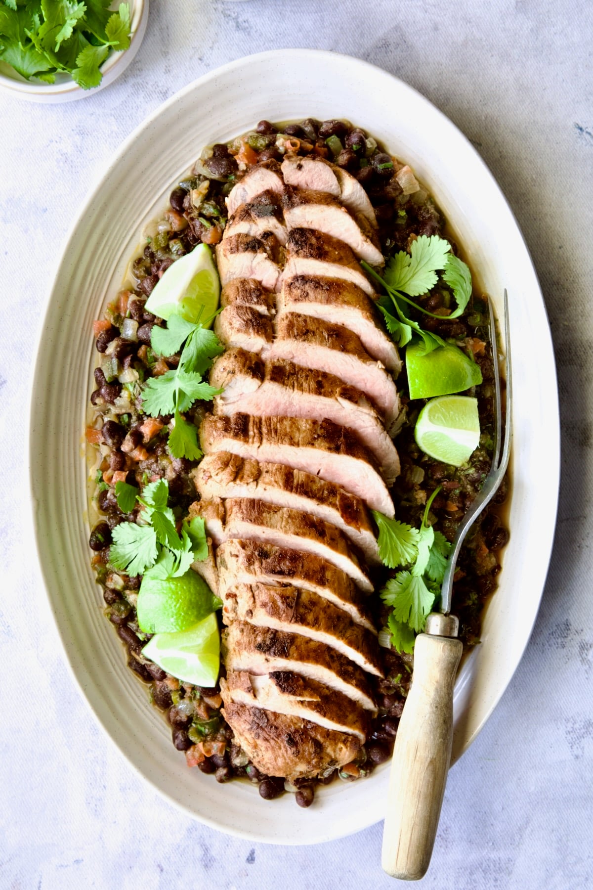 Cuban-Style Pork Tenderloin with Black Beans on oval white platter.