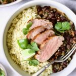 Four slices of Cuban-Style Pork Tenderloin with Black Beans and rice in white bowl.