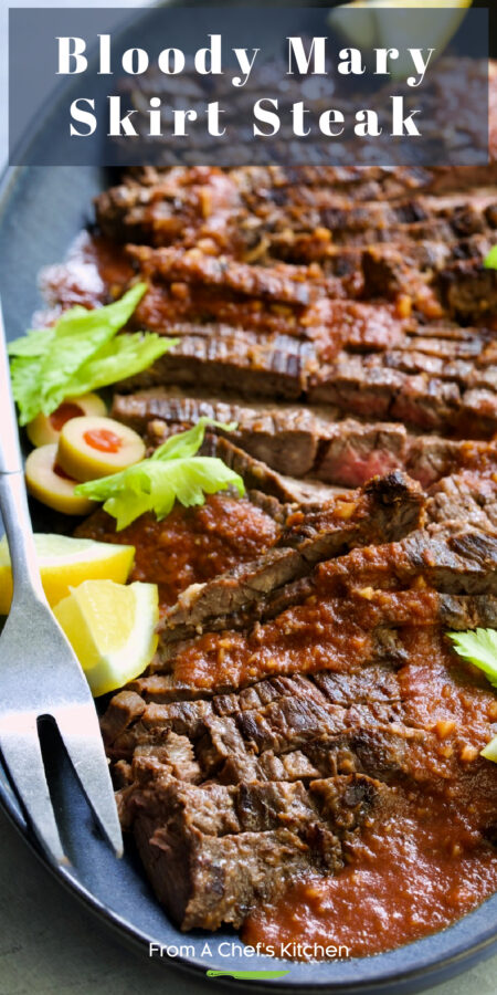 Pinterest graphic for Bloody Mary Skirt Steak showing it on a blue platter garnished with lemon wedges, celery leaves and sliced green olives.