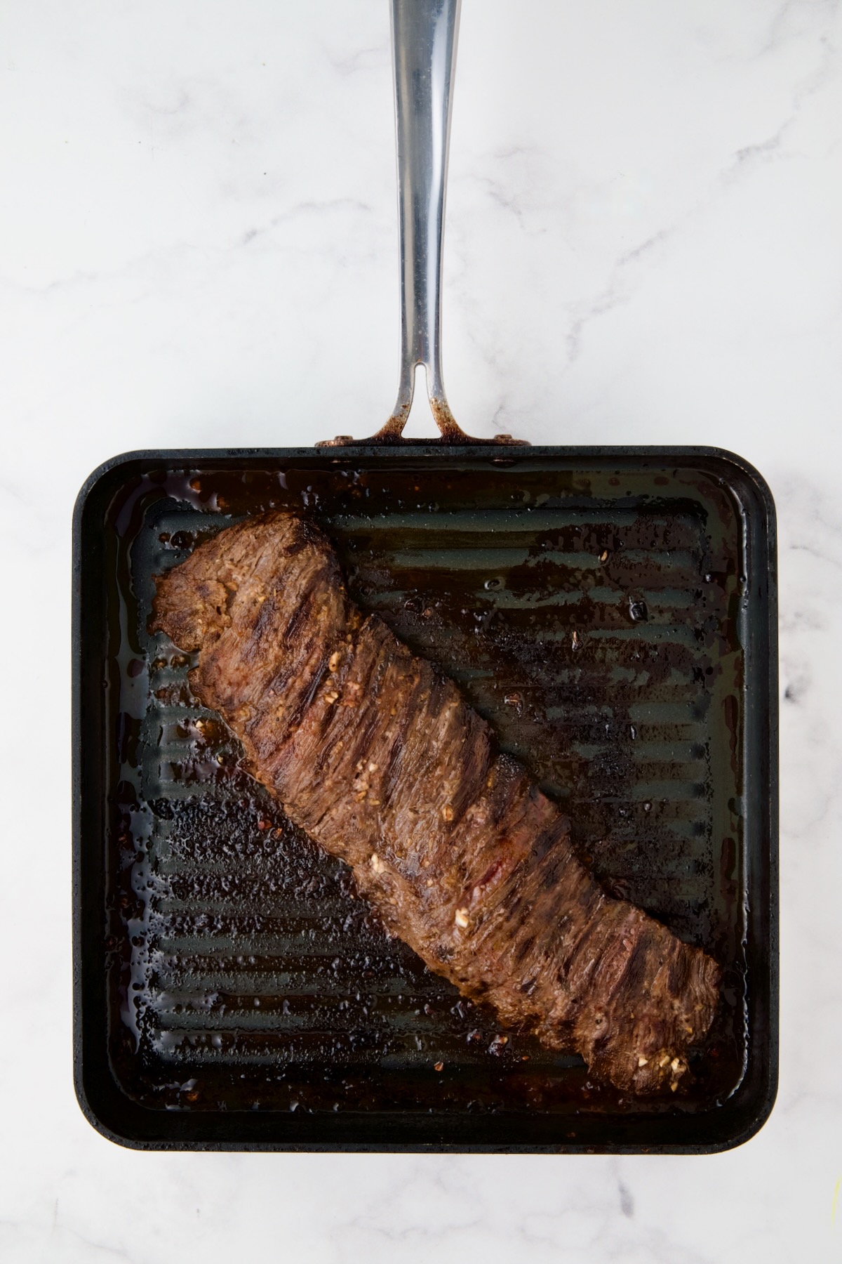 Grilled skirt steak on square grill pan.